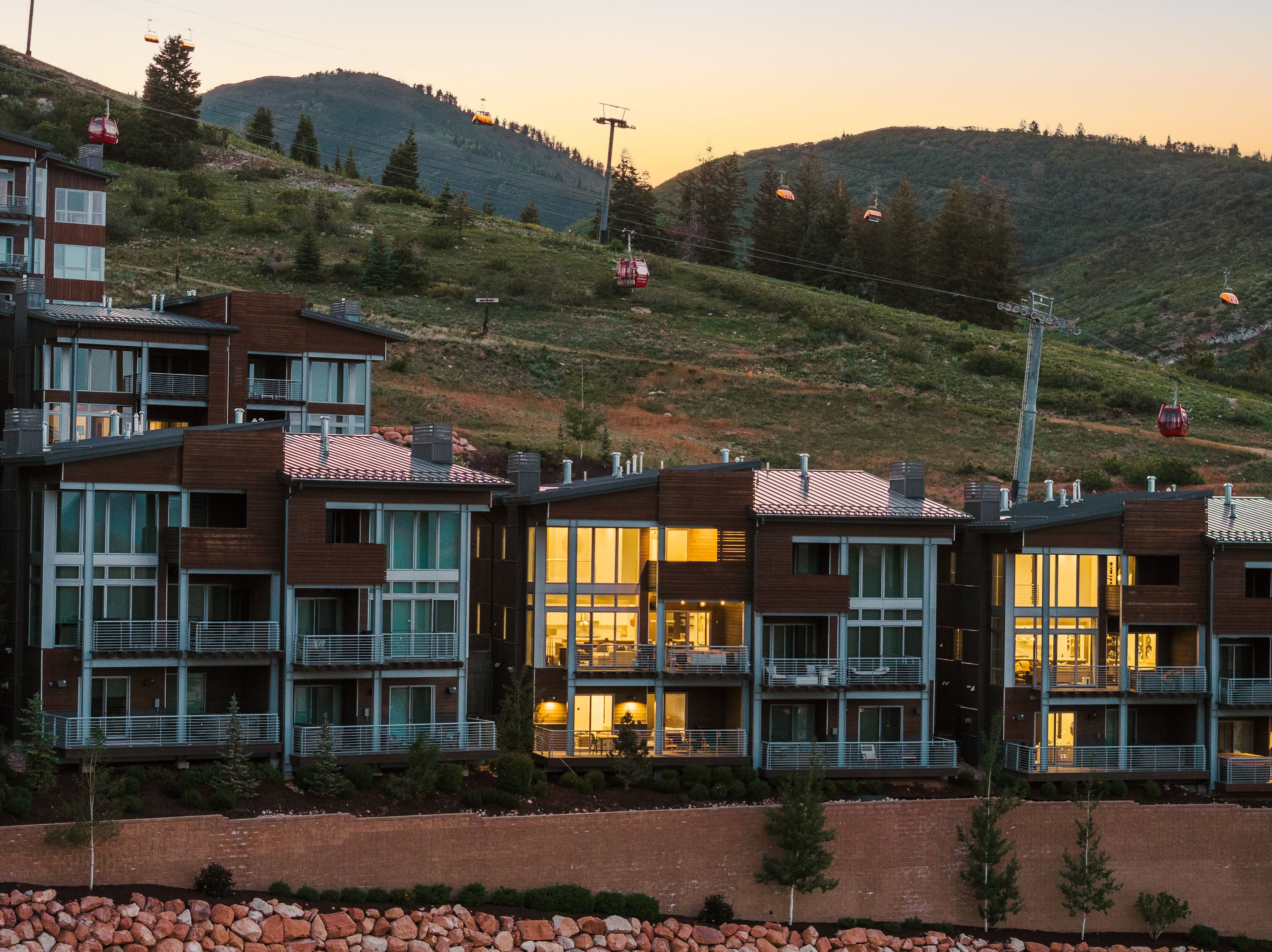 Contemporary multi-level residences featuring expansive window walls, private balconies with glass railings, and a rich wood and stucco exterior