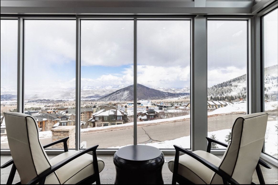 Floor-to-ceiling windows with metal framing showcasing a mountain landscape and distant structures