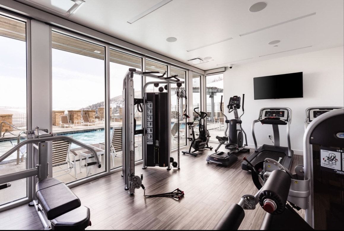 Fitness center featuring floor-to-ceiling windows, wood-finish flooring, recessed lighting, and a wall-mounted display