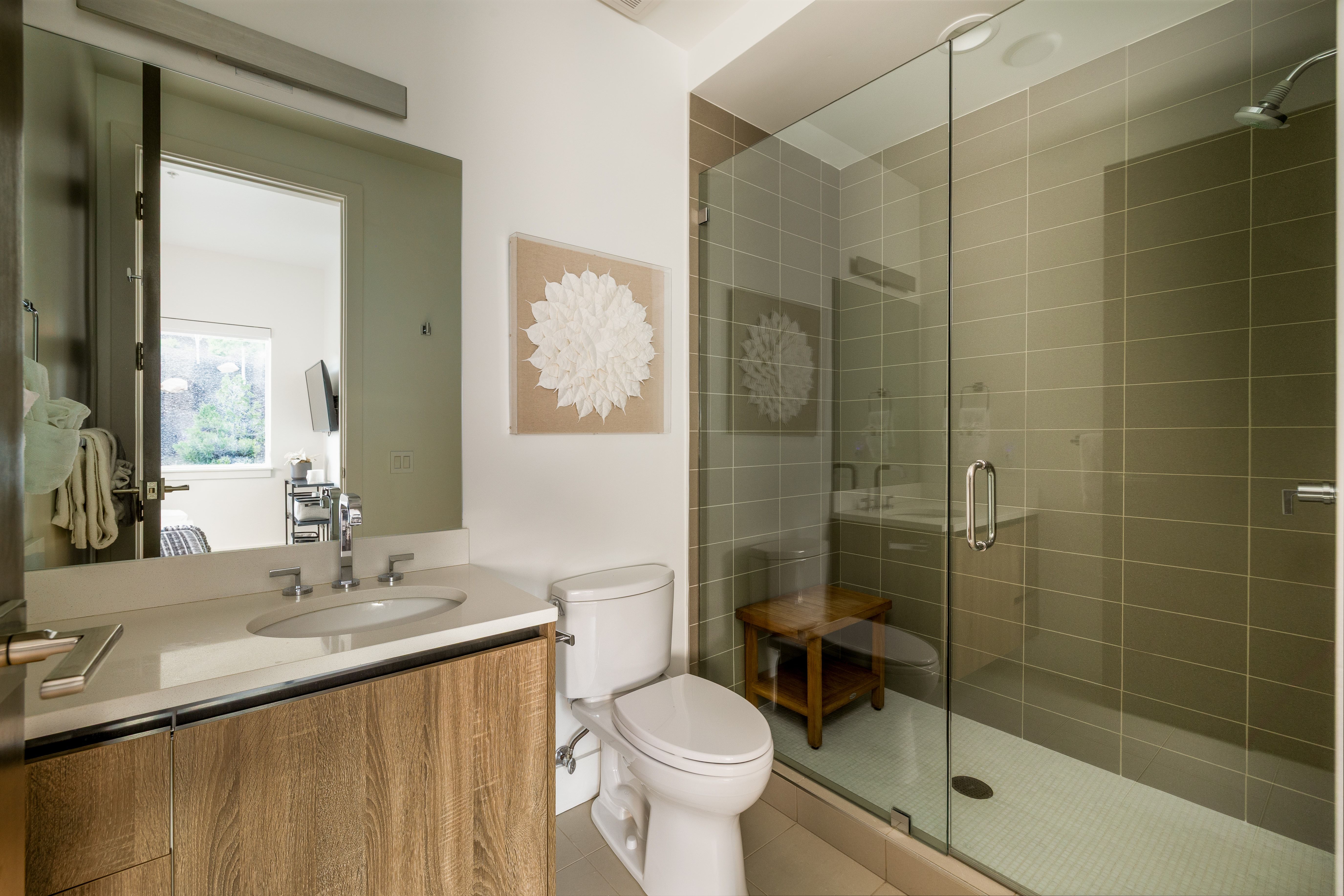 Contemporary bathroom featuring a spacious glass-enclosed shower, wood-finish vanity with an undermount sink, quartz countertop, and large format wall tiling