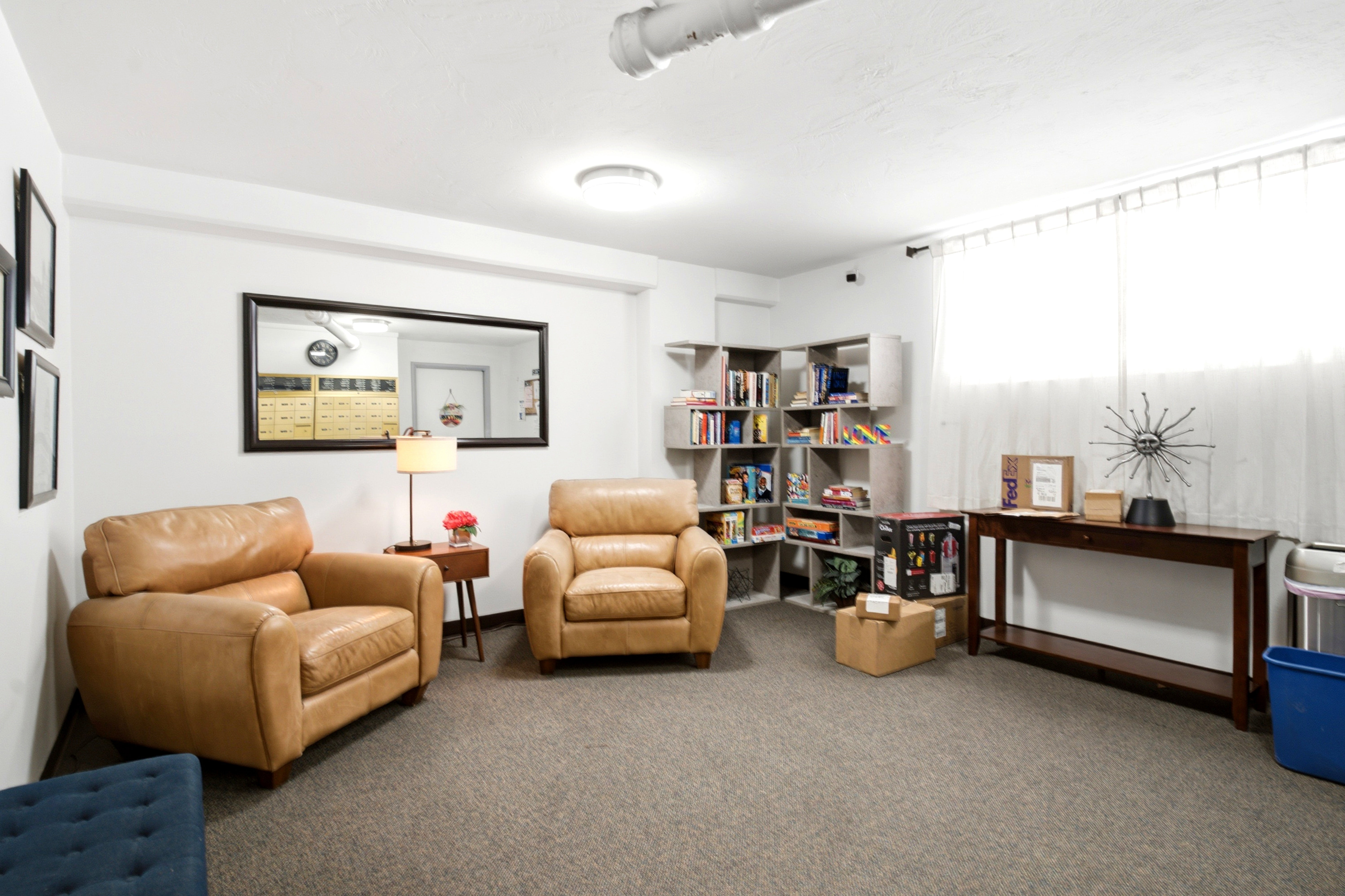 Carpeted room featuring white walls, a mounted mirror, and built-in shelving