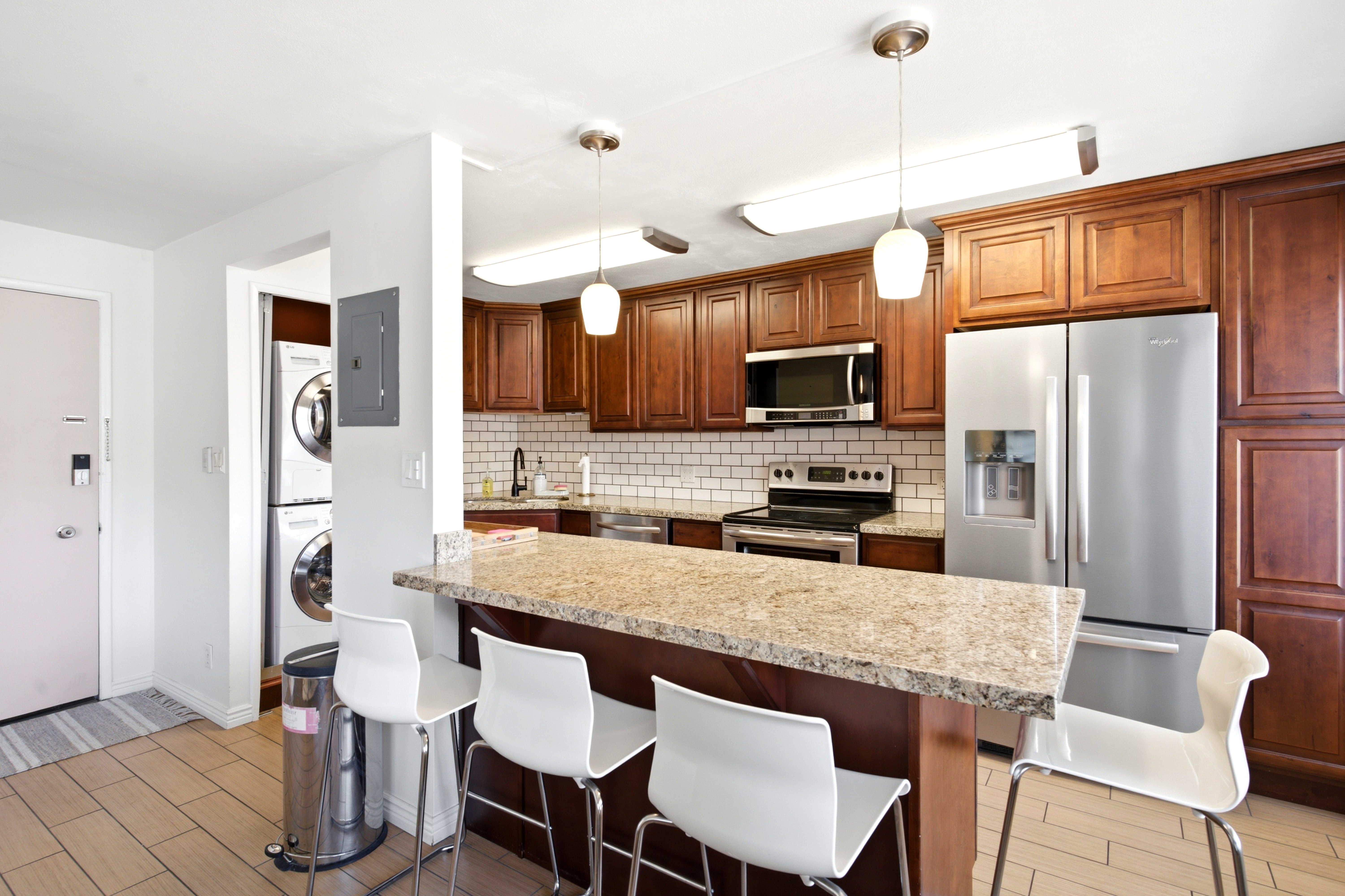 Kitchen featuring wood cabinetry, stainless steel appliances, subway tile backsplash, and a breakfast bar with a light-colored countertop