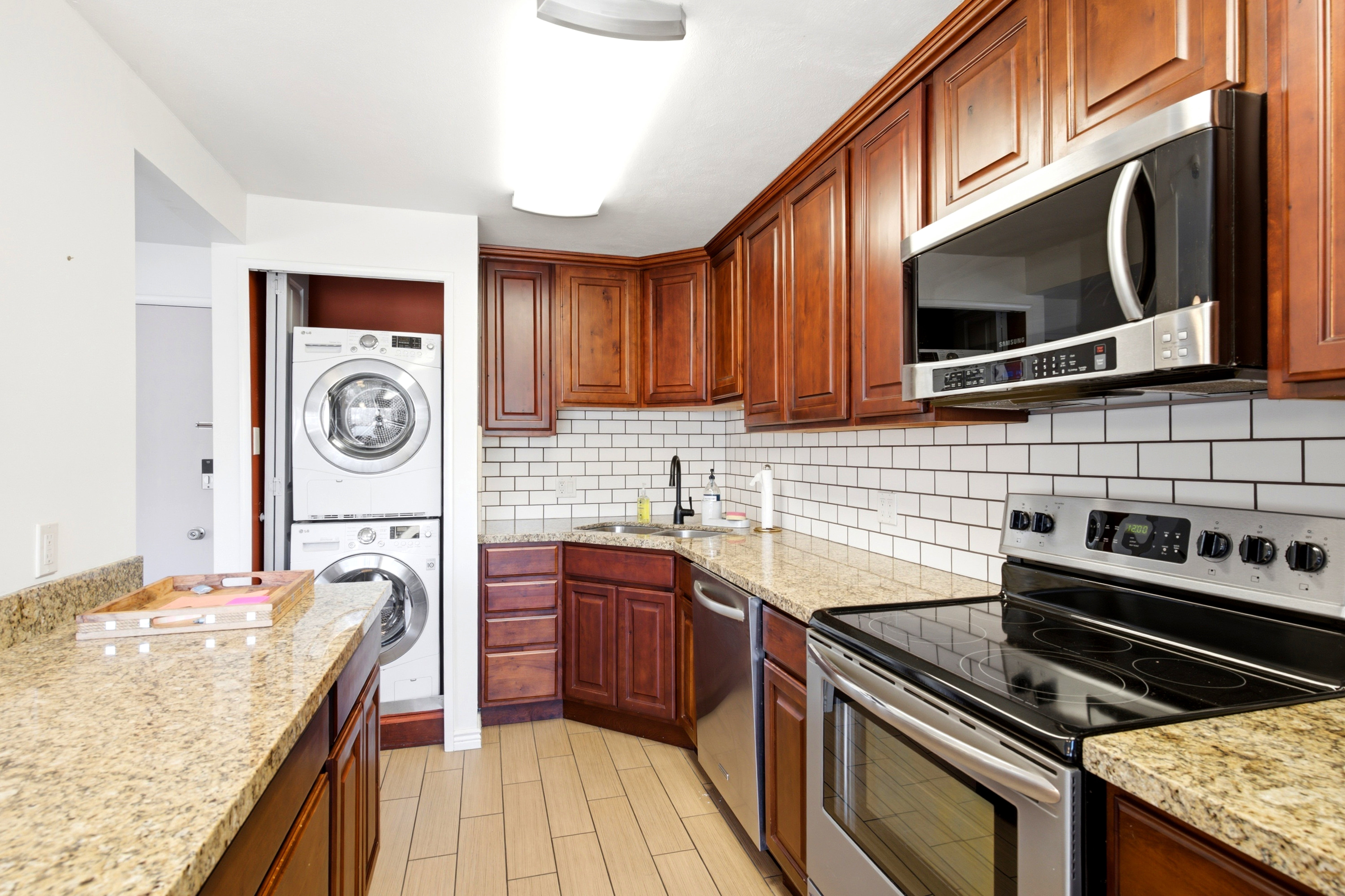 Kitchen featuring wood cabinetry, light-colored speckled countertops, and a white subway tile backsplash