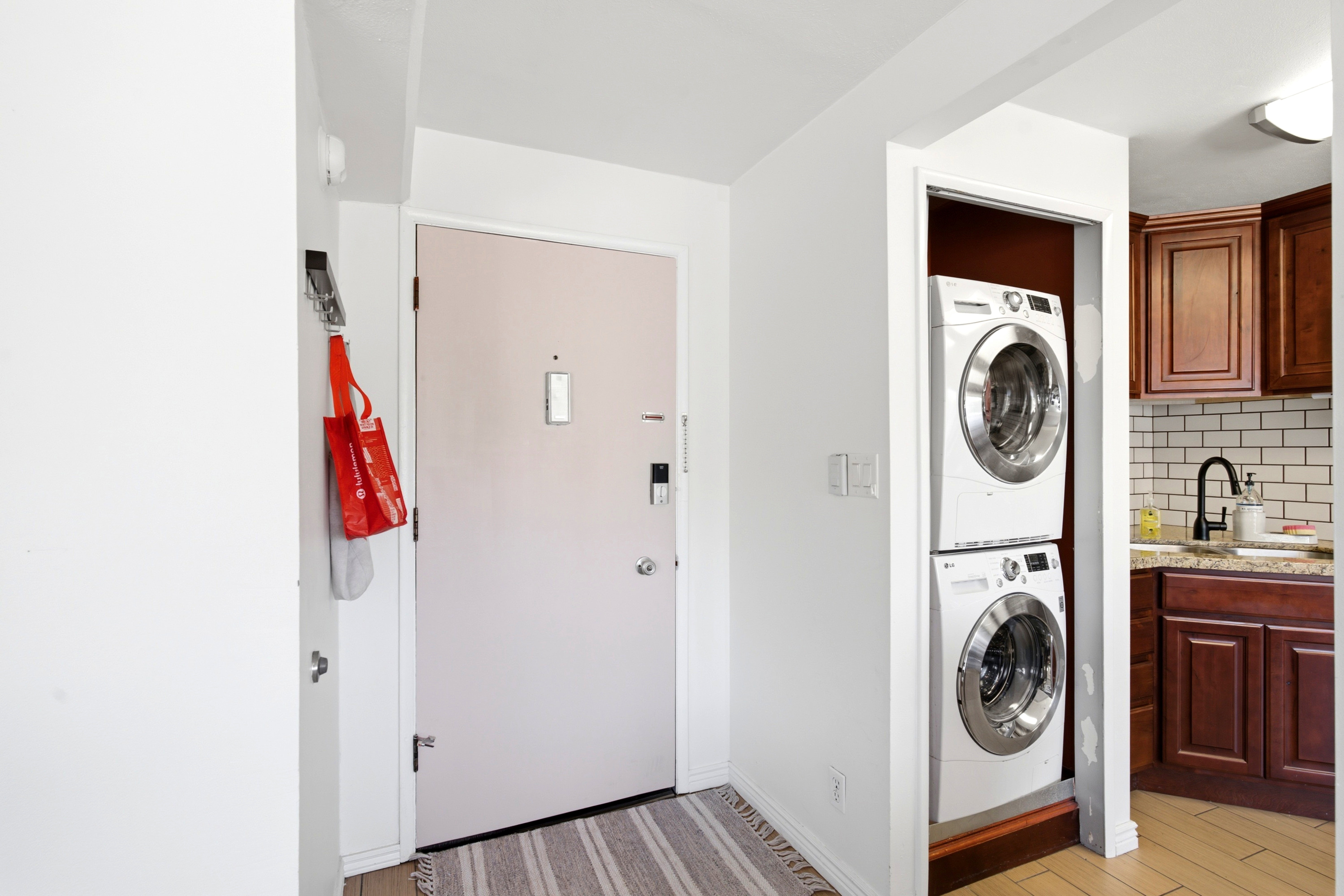 Entryway featuring a stacked washer and dryer unit, wood-finish flooring, and a white interior door