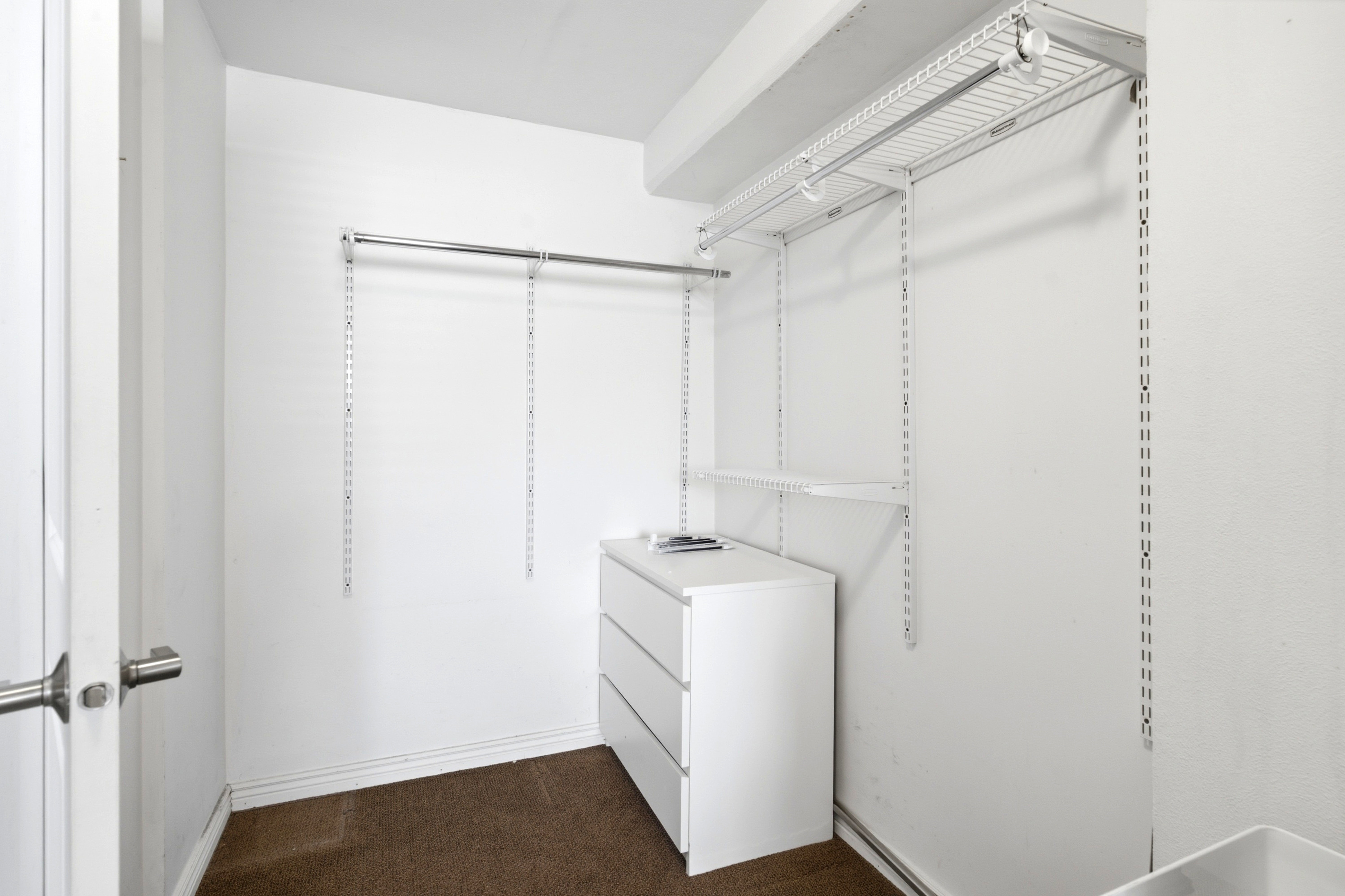 Closet featuring adjustable wire shelving, a clothing rod, white baseboards, and carpet flooring