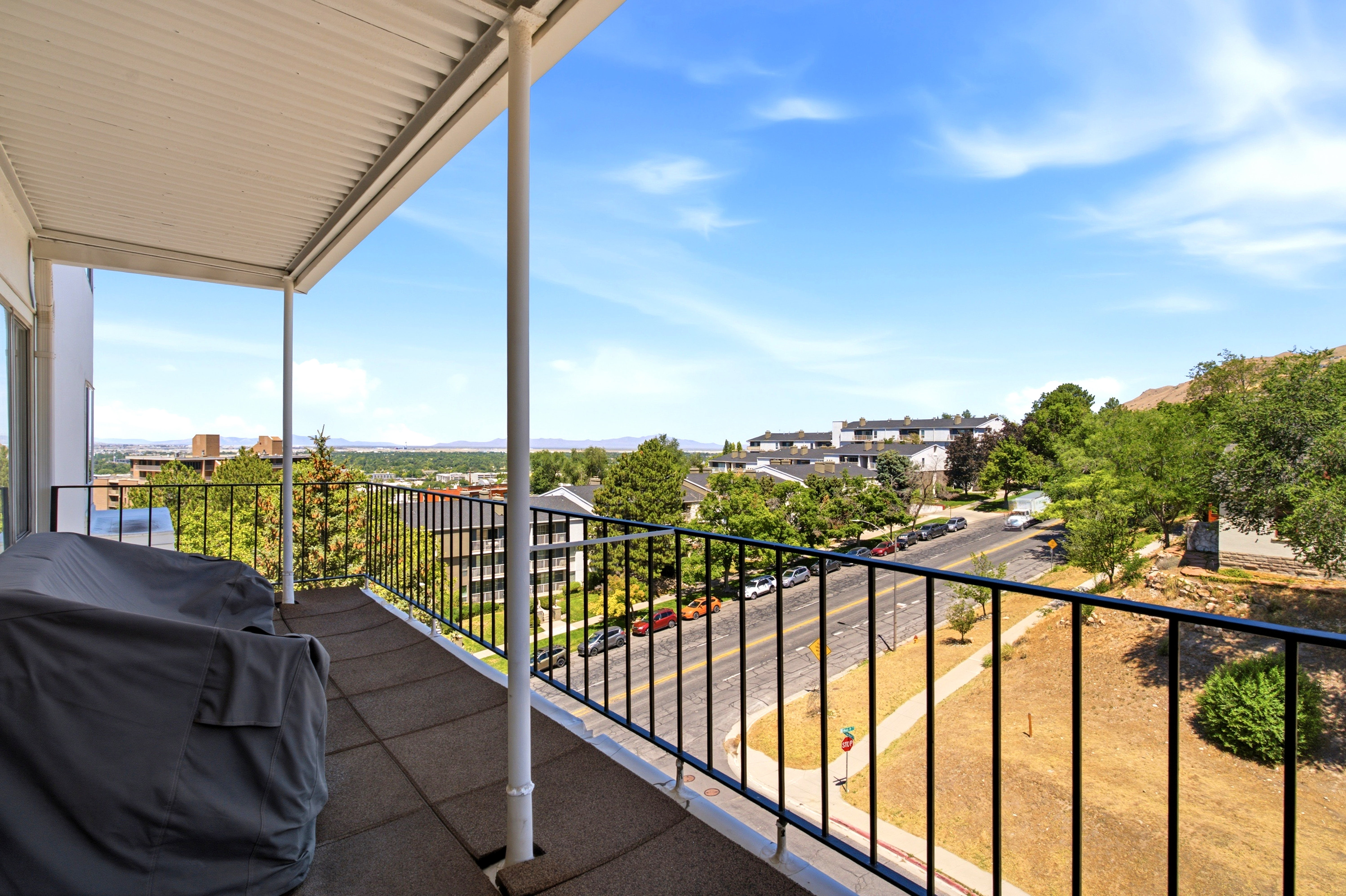 Covered balcony featuring tile flooring and a black metal railing