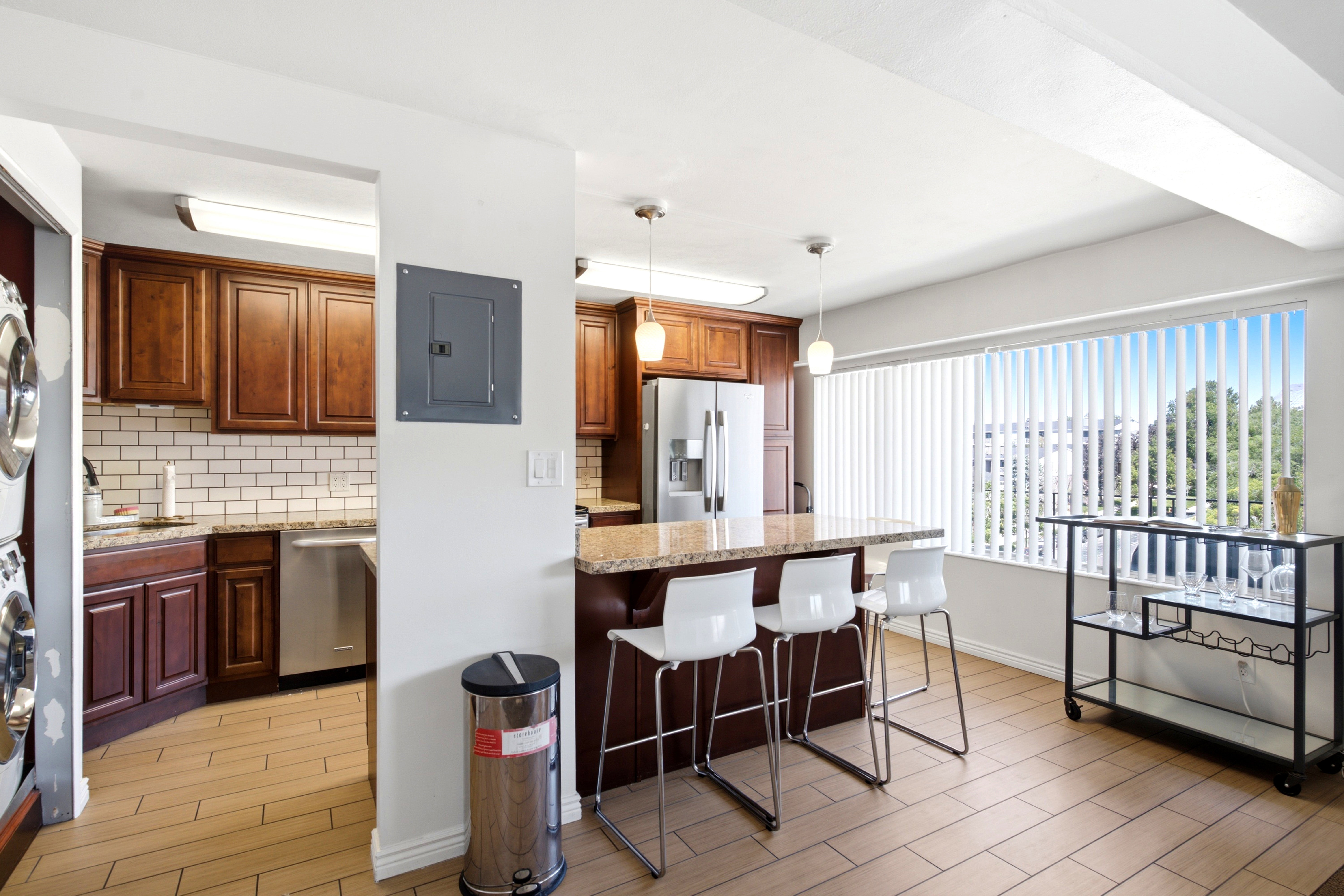 Kitchen featuring rich wood cabinetry, granite countertops, a subway tile backsplash, and stainless steel appliances