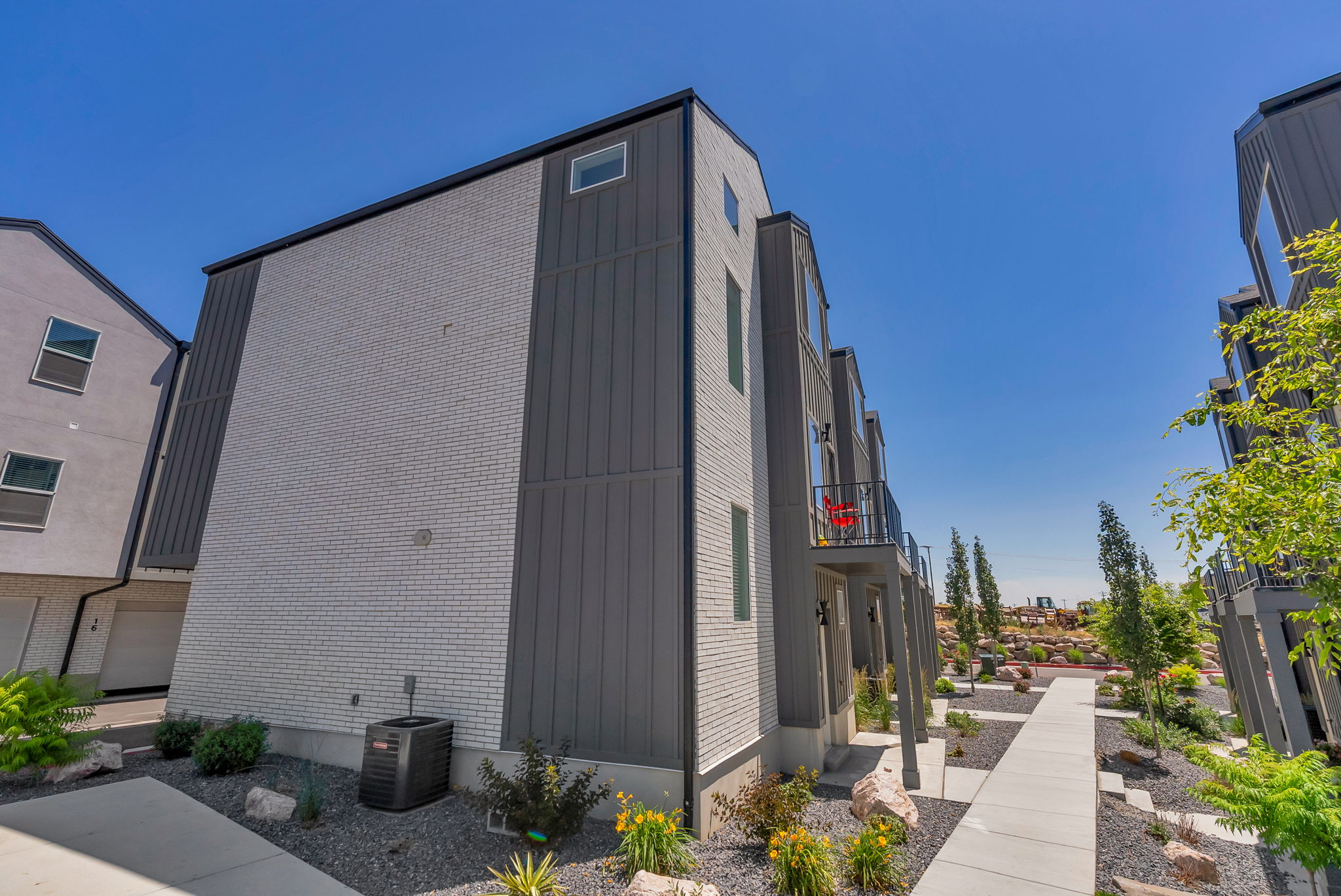 Modern townhouse exterior featuring a white brick and vertical siding facade