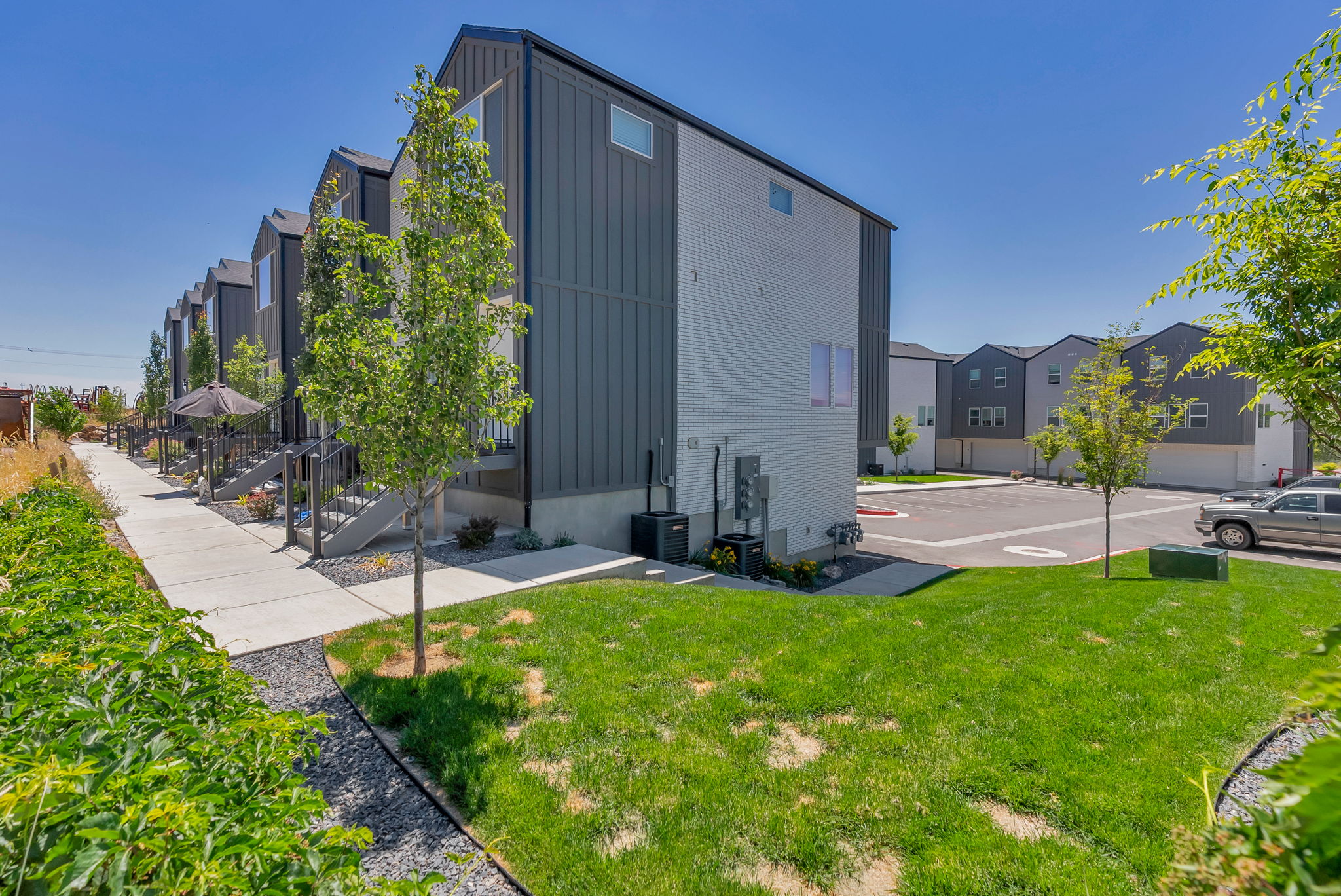 Modern townhome exterior featuring vertical metal siding and light-colored brick accents