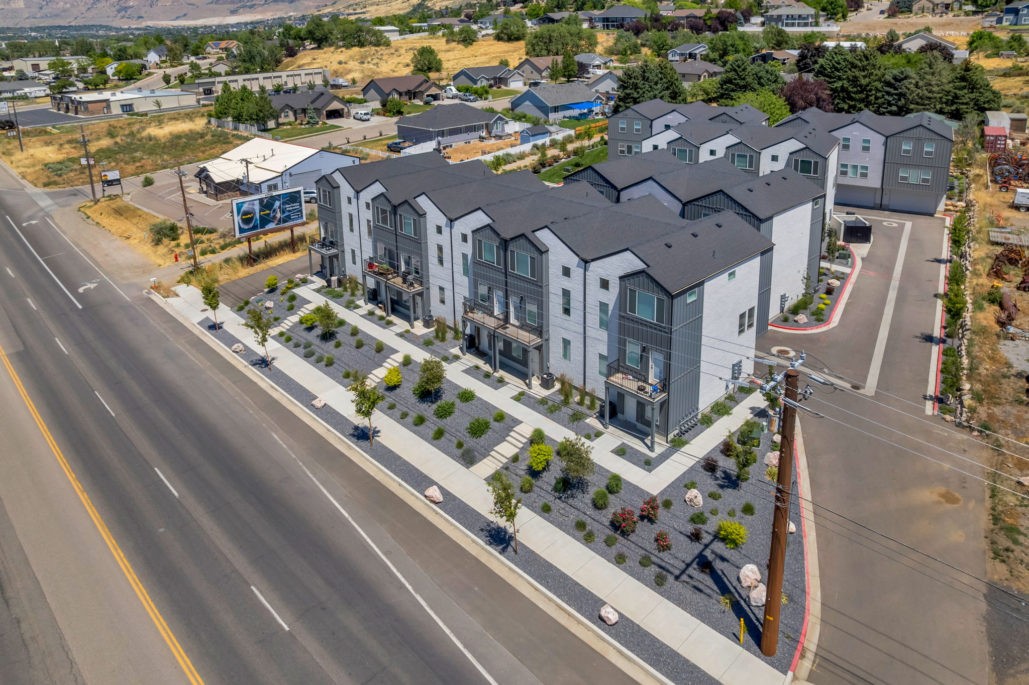 Modern multi-story residential complex featuring contemporary architecture, private balconies, and contrasting dark and light exterior siding