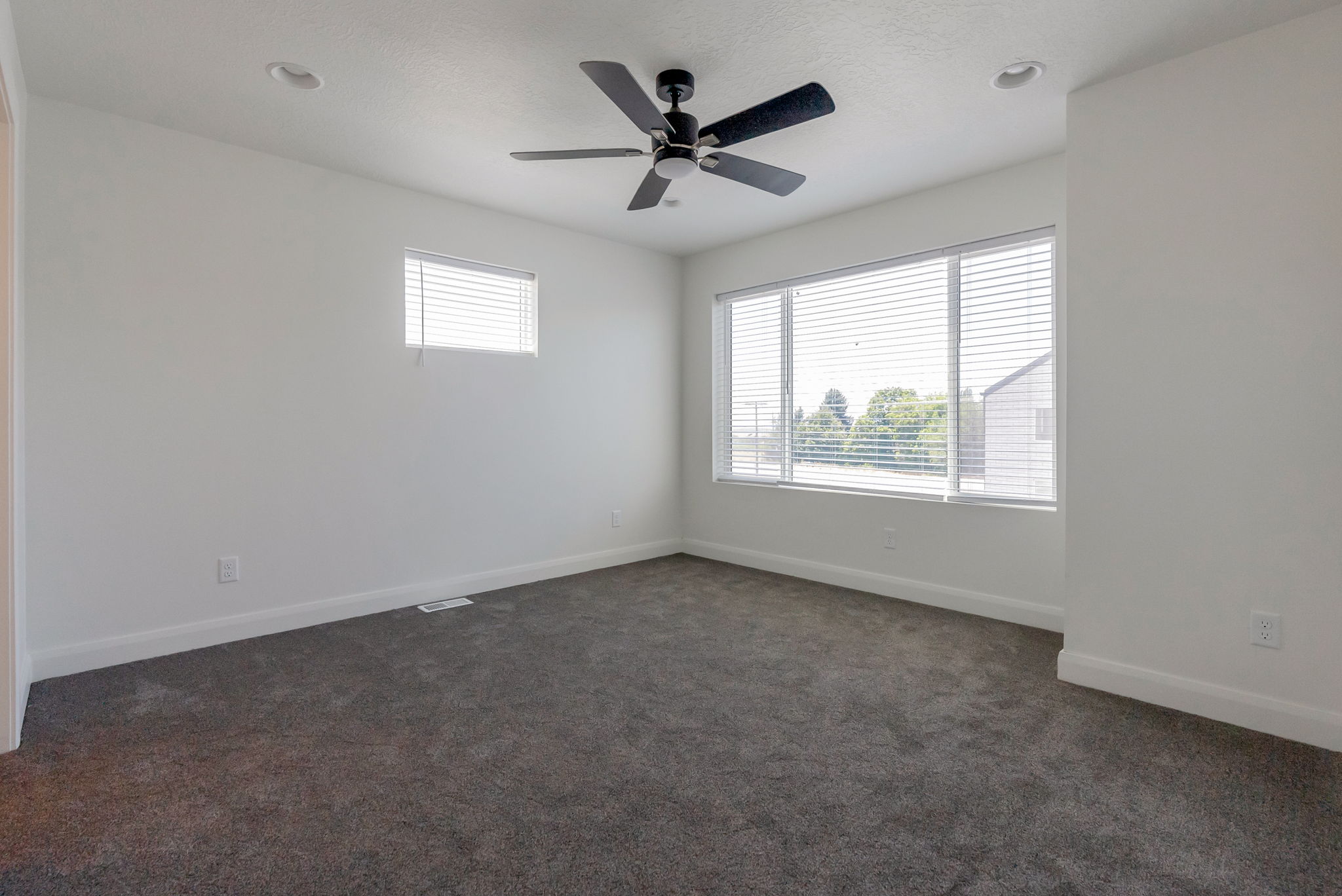 Carpeted room featuring a large window, a smaller horizontal window, a ceiling fan, and recessed lighting