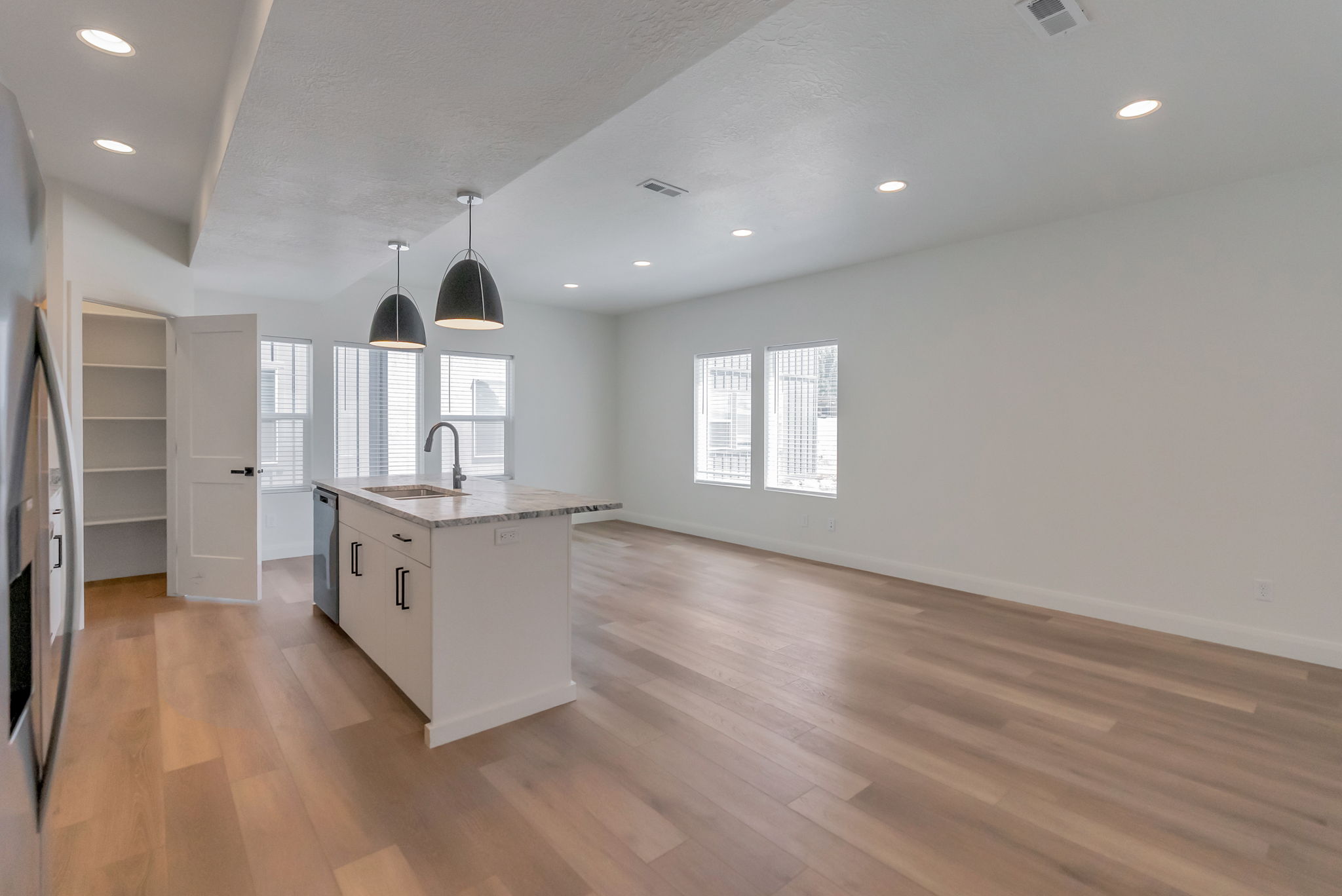 Open-concept area featuring light wood-finish flooring, recessed lighting, and white walls