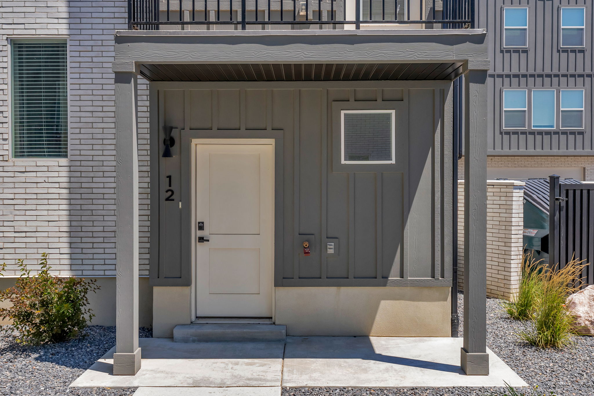 Covered entryway with concrete landing, featuring a white paneled door and board and batten siding