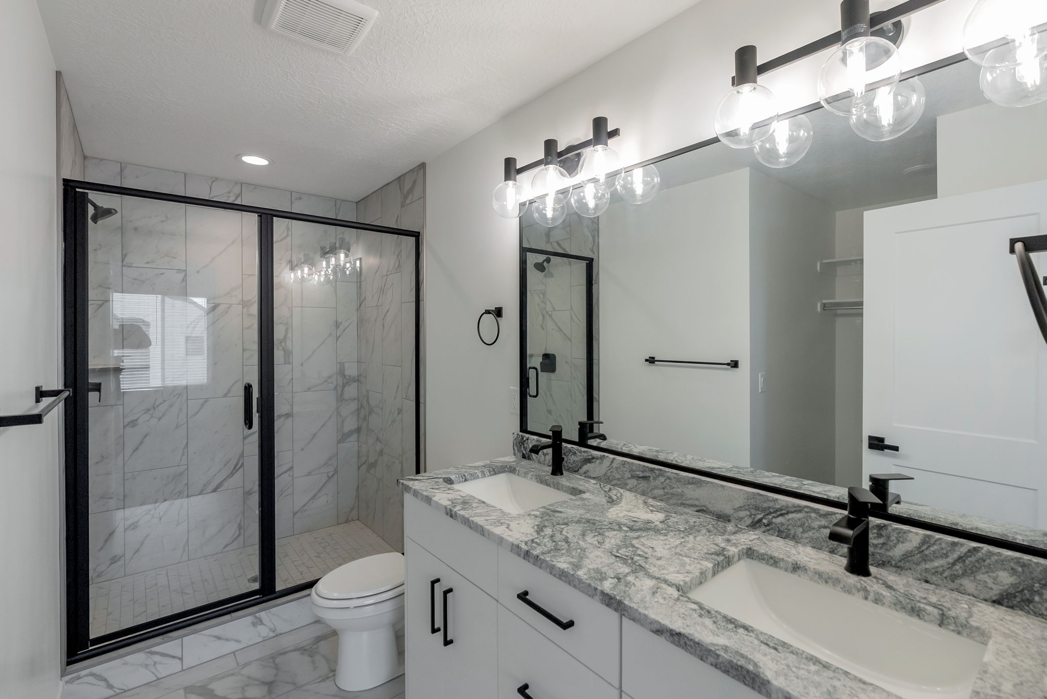 Double vanity featuring stone countertops and two undermount sinks with matte black faucets