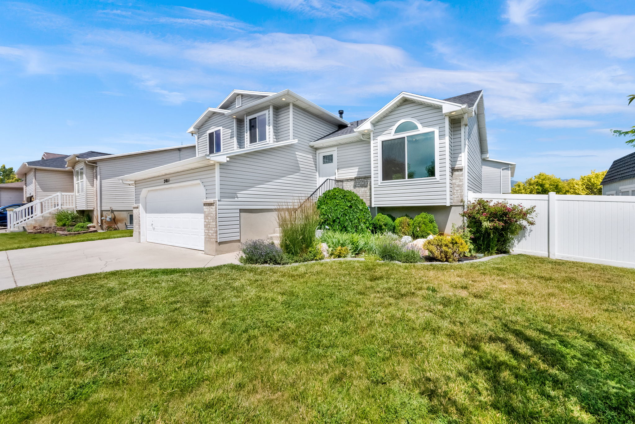 Contemporary residence featuring light gray siding, an attached two-car garage, and a concrete driveway