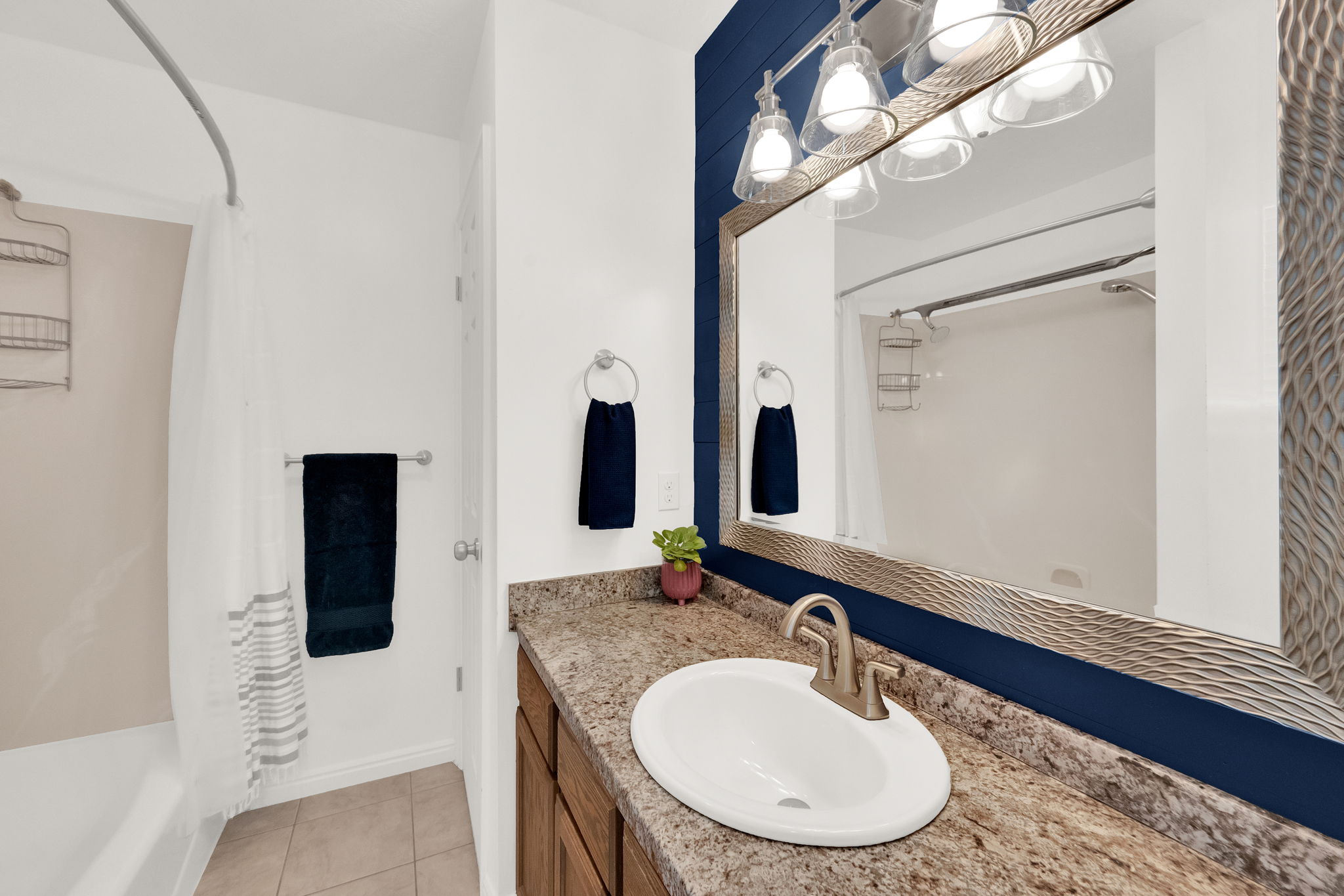 Bathroom featuring a single basin vanity with a granite-style countertop, brushed nickel faucet, and wood-finish cabinetry