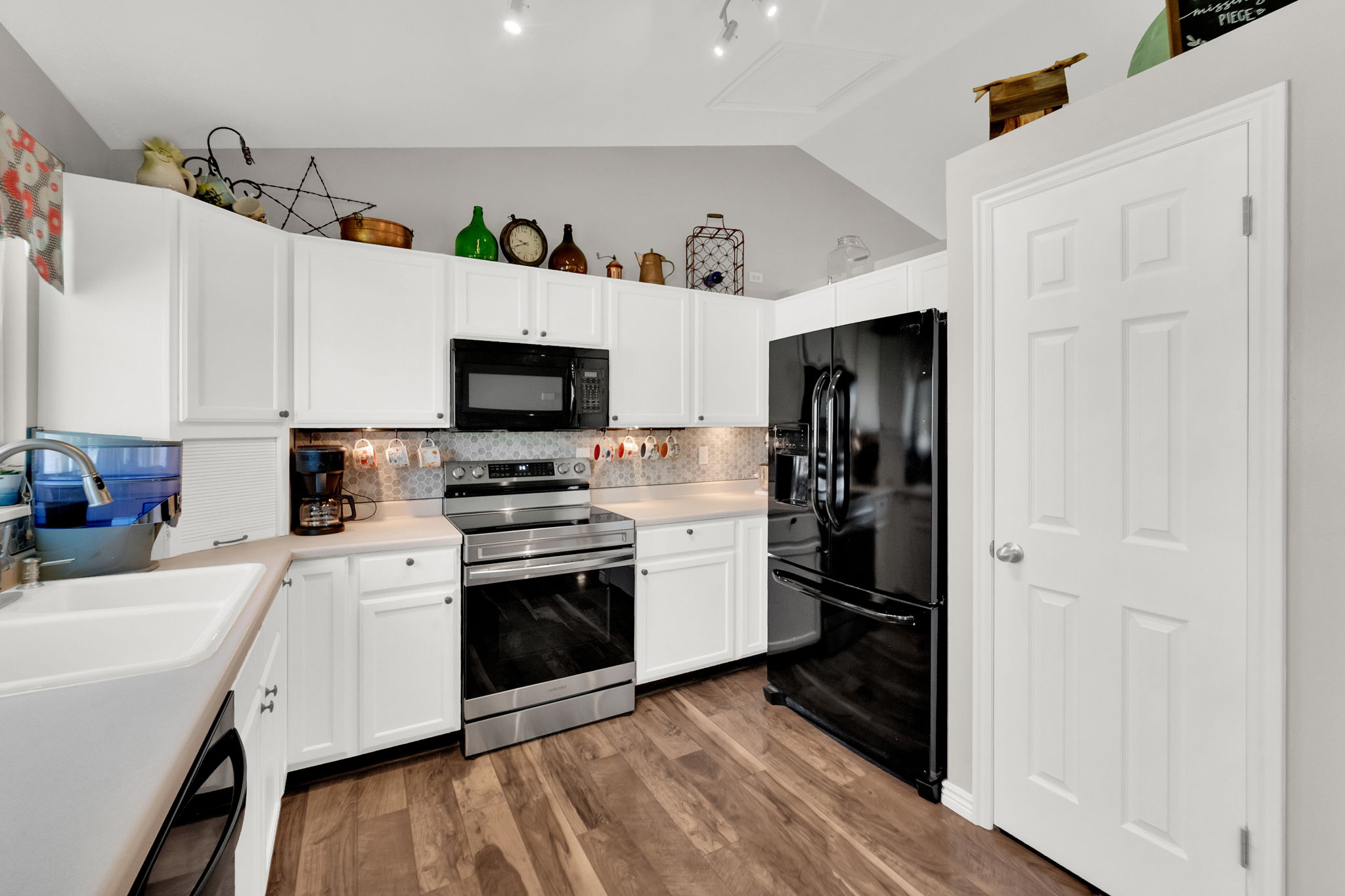 Kitchen featuring white cabinetry, light countertops, wood-finish flooring, a stainless steel range, and a mosaic tile backsplash
