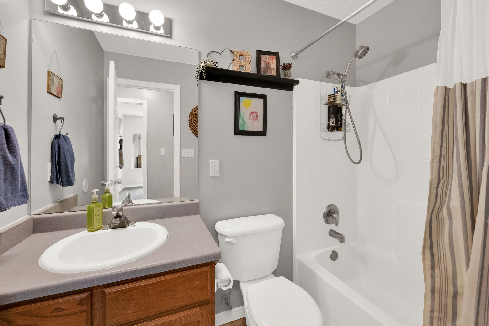 Full bathroom featuring a single vanity with a laminate countertop, a white oval sink, and a wood-finish cabinet base