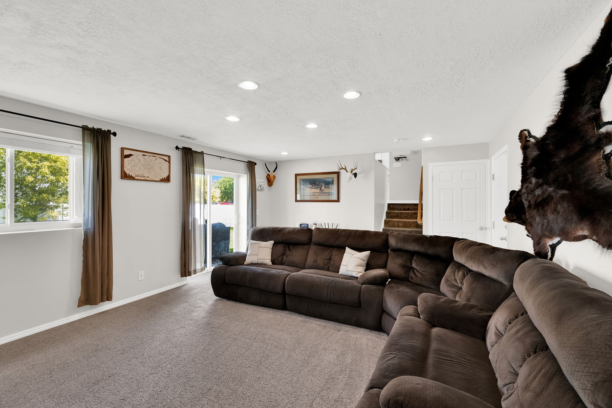 Spacious recreational room featuring recessed lighting, a sliding glass door to exterior, and neutral carpeting