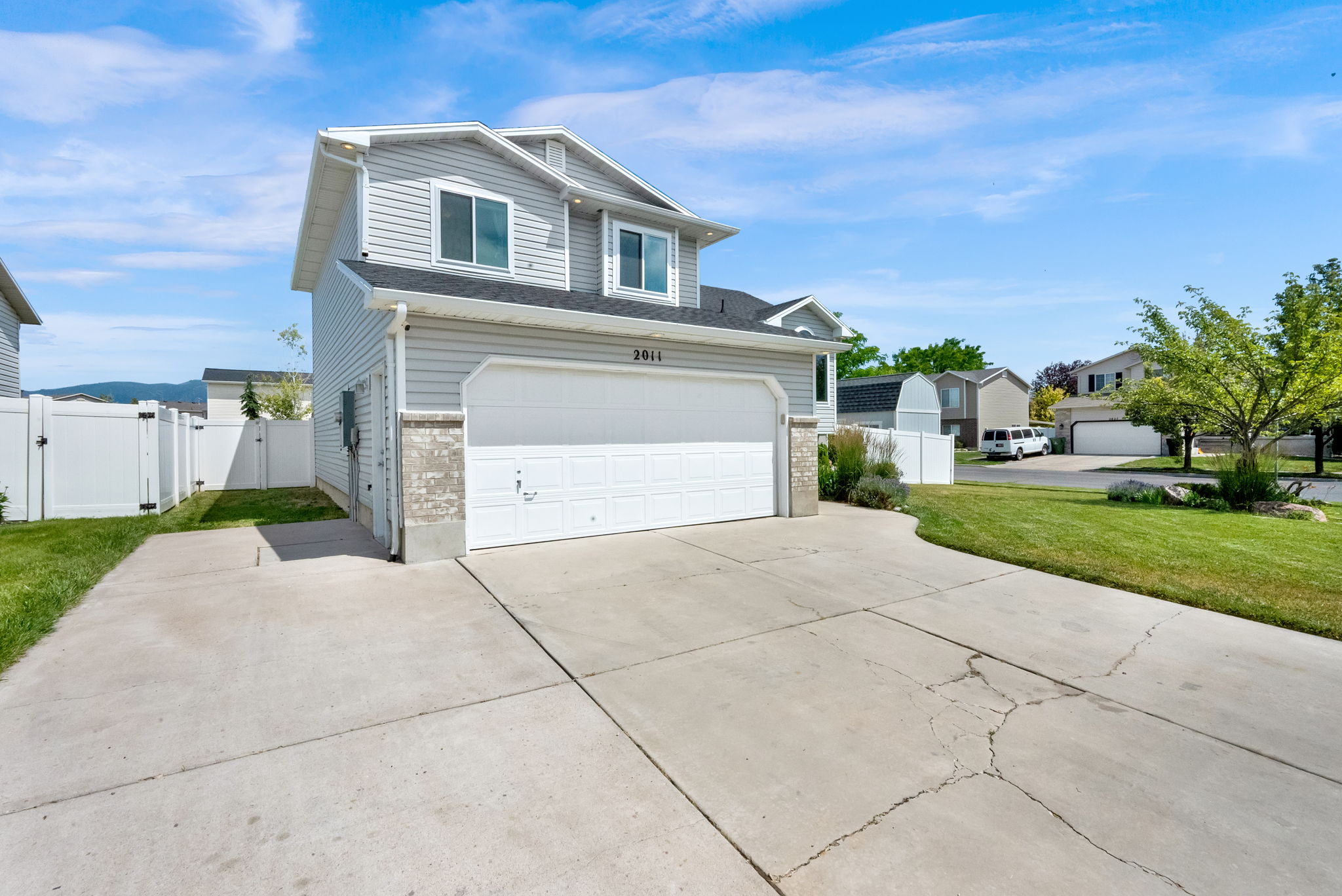 Two-story residence featuring light gray siding, a two-car garage with a white door, and a concrete driveway