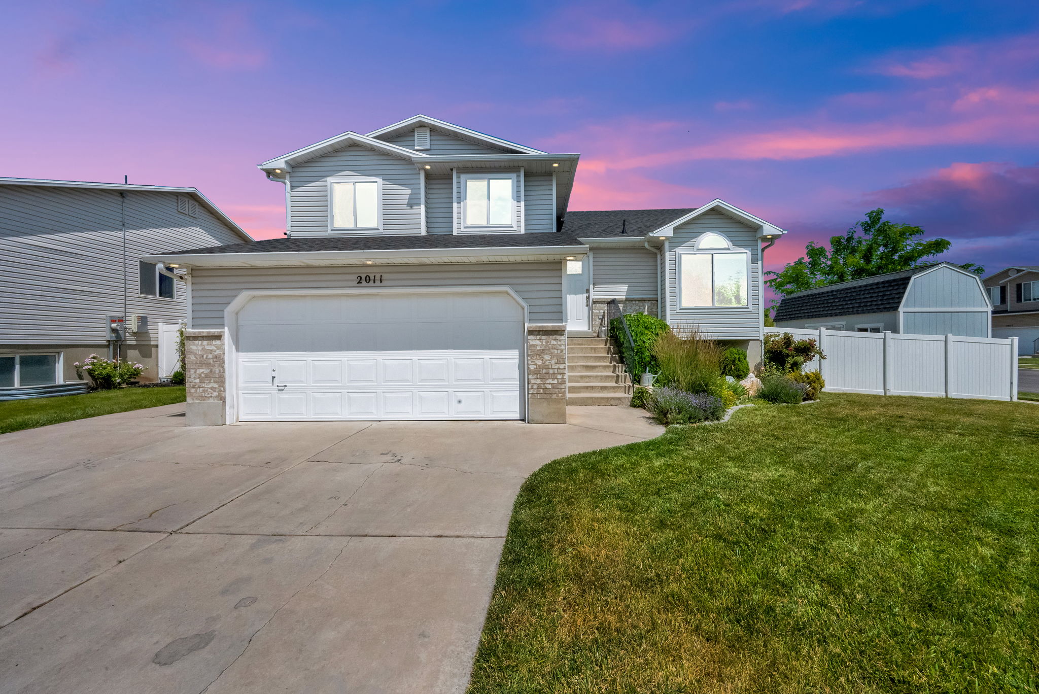 Two-story home with a two-car garage, concrete driveway, and gray vinyl siding