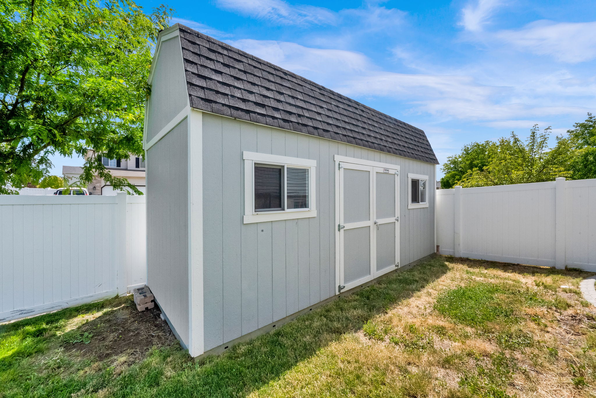 Detached shed featuring a gambrel roof and light-colored siding