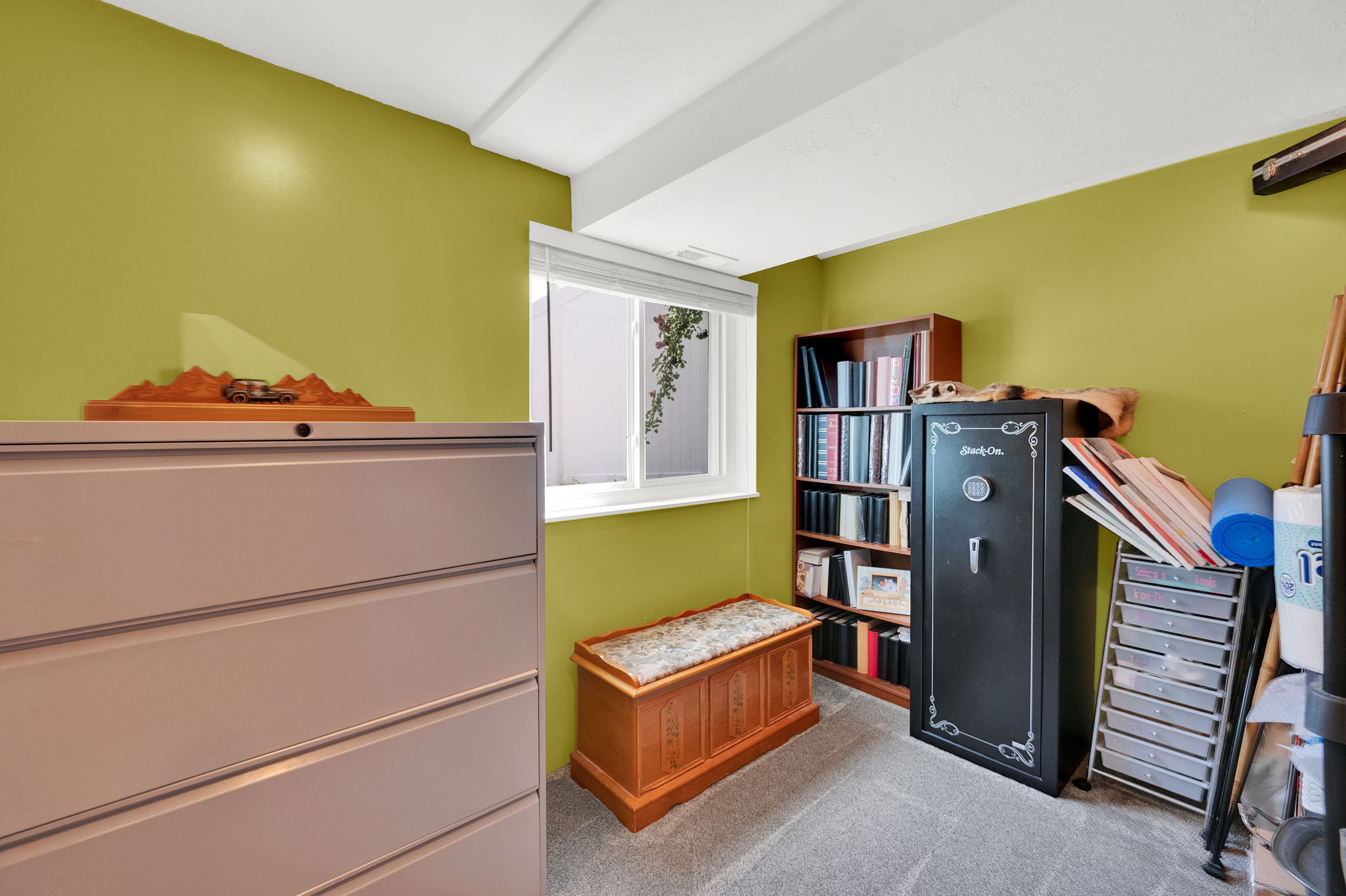 Versatile room featuring an egress window, light green walls, and gray carpet flooring