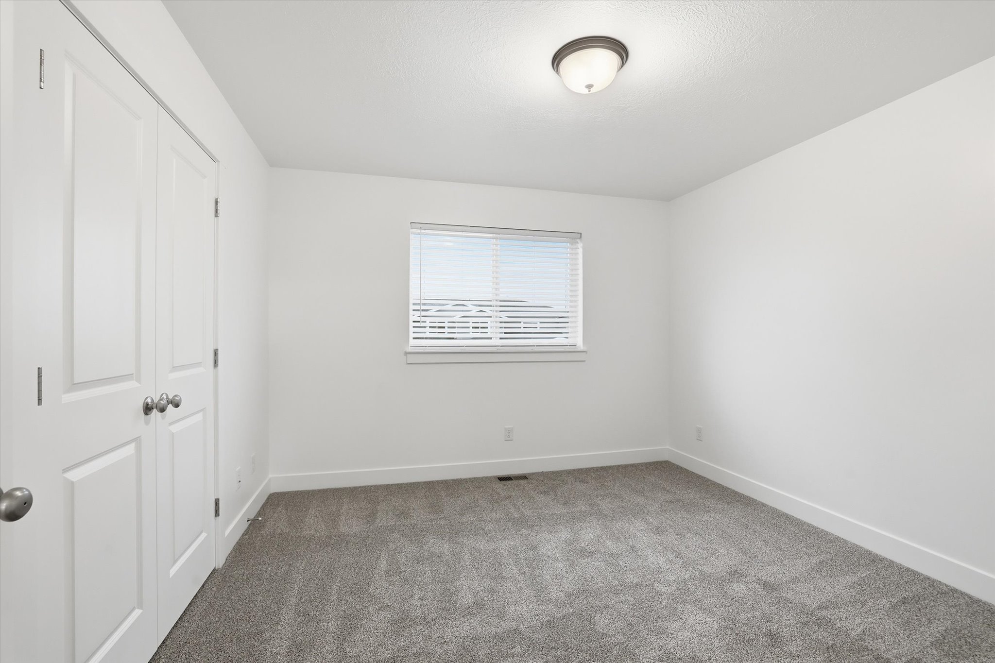 Room featuring neutral gray carpet, white walls, and a window with horizontal blinds