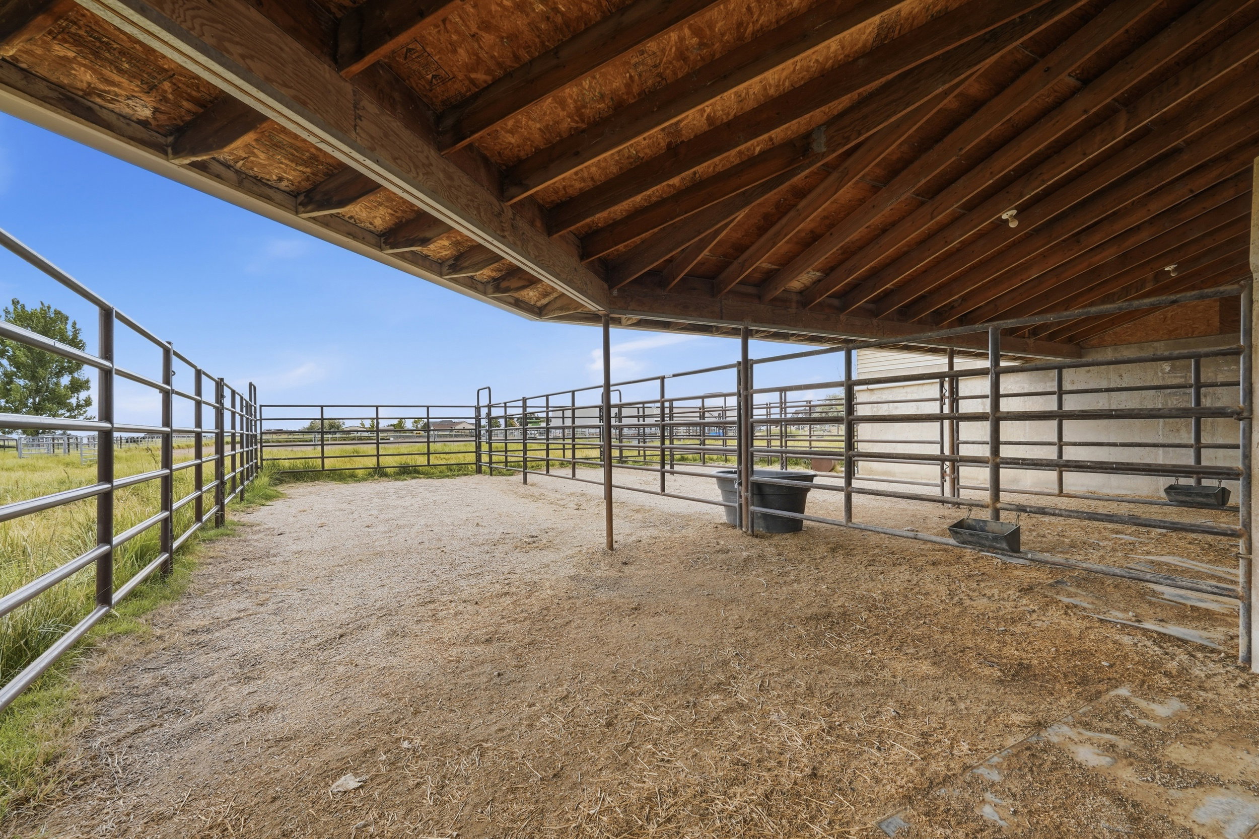 Covered animal pen featuring metal fencing, a high wood-finish ceiling, and a large open-air section