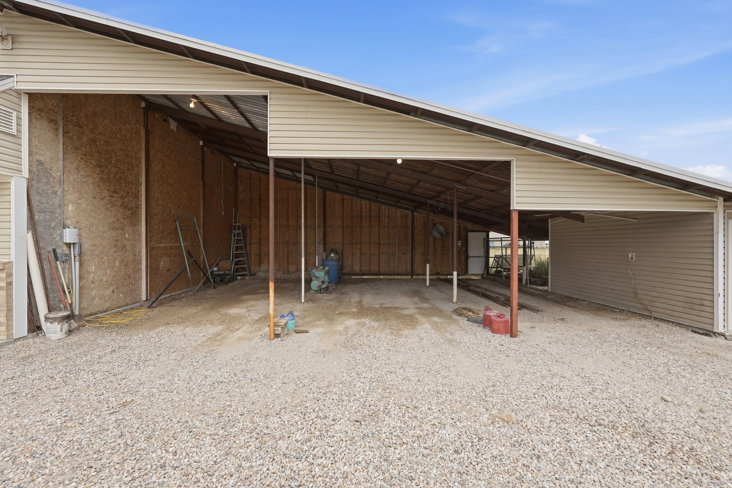 Expansive covered structure featuring a gravel floor, metal roofing, and exposed wood siding