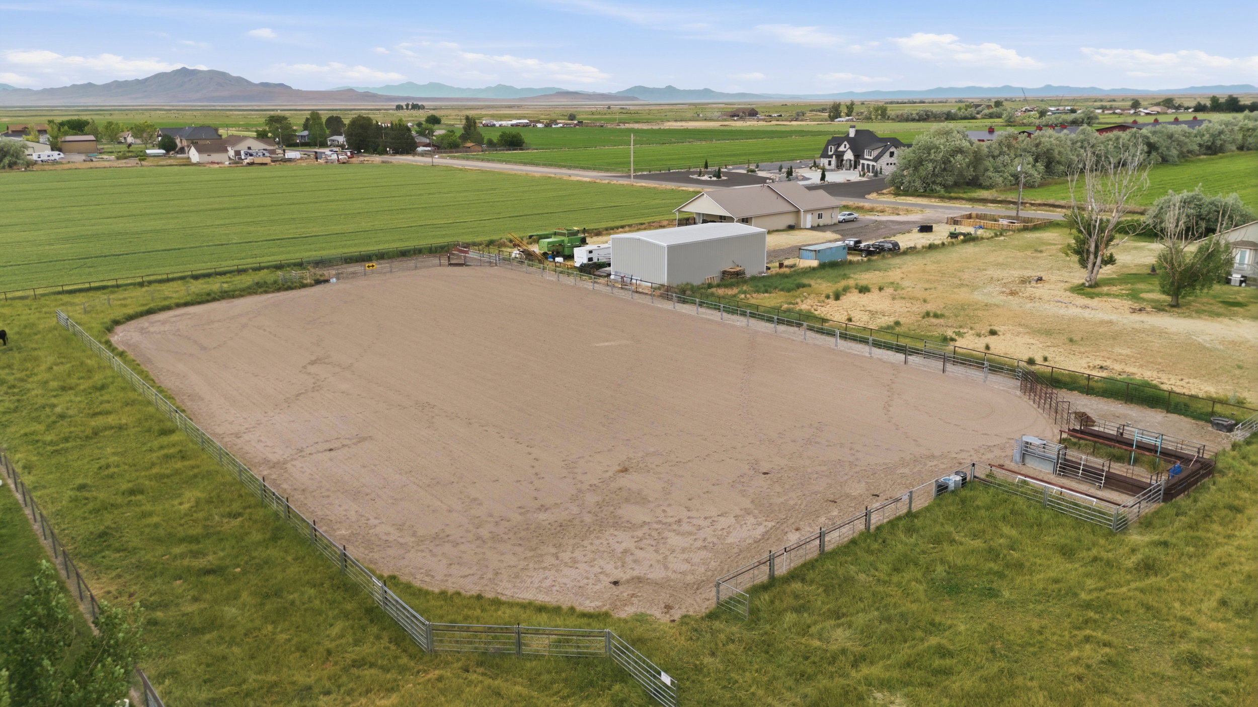Expansive fenced equestrian arena with a sand surface and adjacent corrals