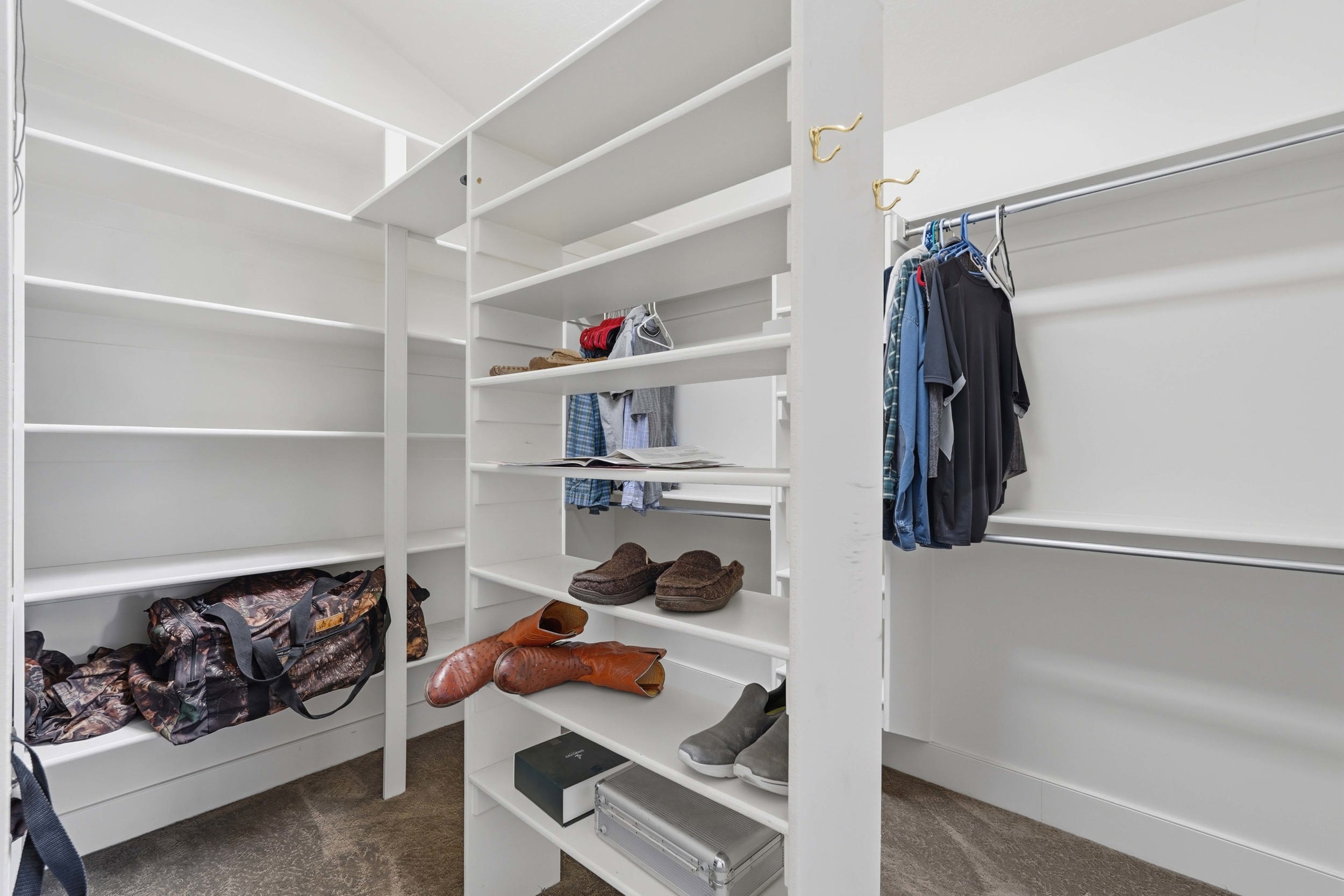 Walk-in closet featuring extensive built-in shelving, multiple hanging rods, and integrated storage solutions
