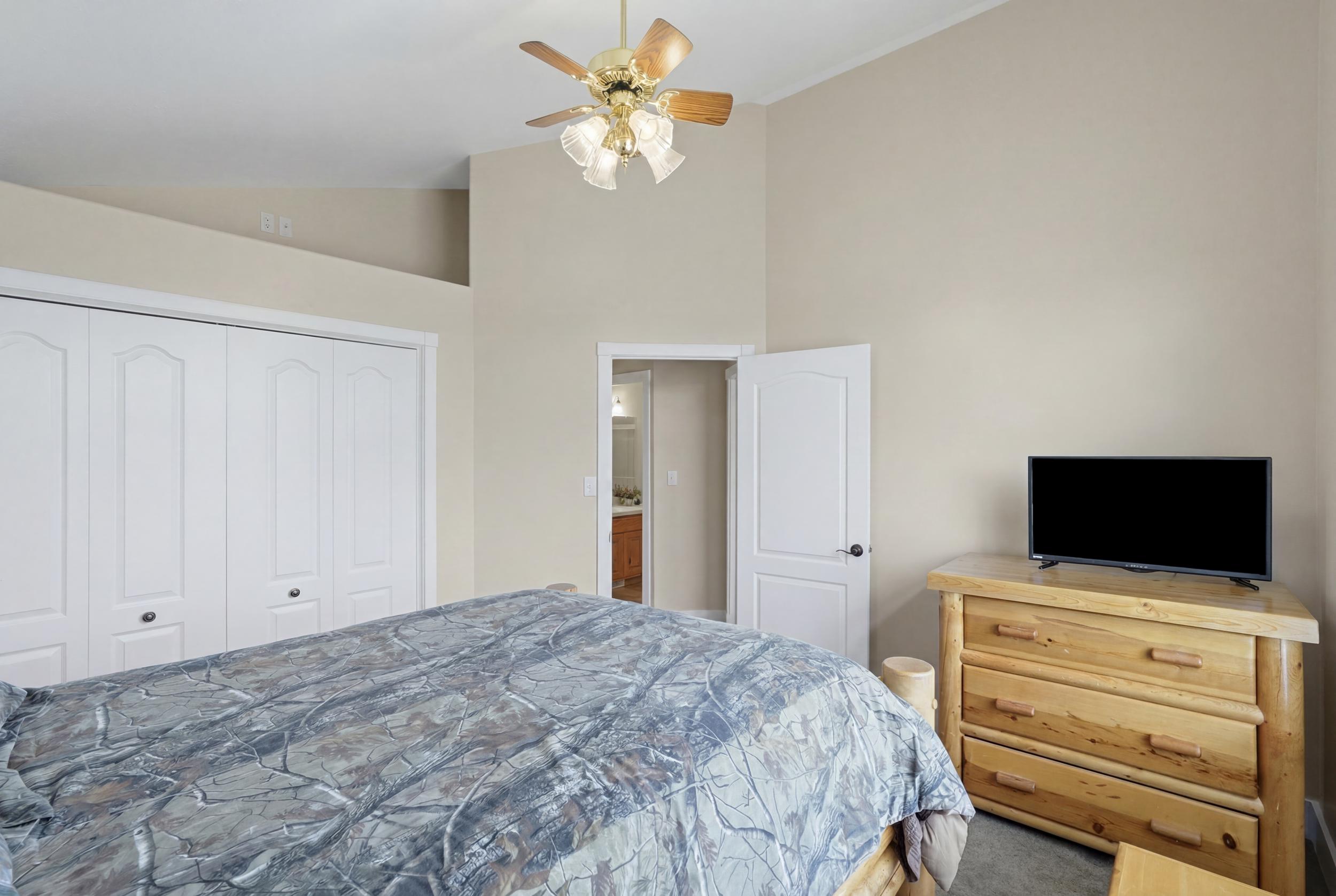 Vaulted ceiling with a ceiling fan light fixture, two-panel bifold closet doors, and neutral wall paint