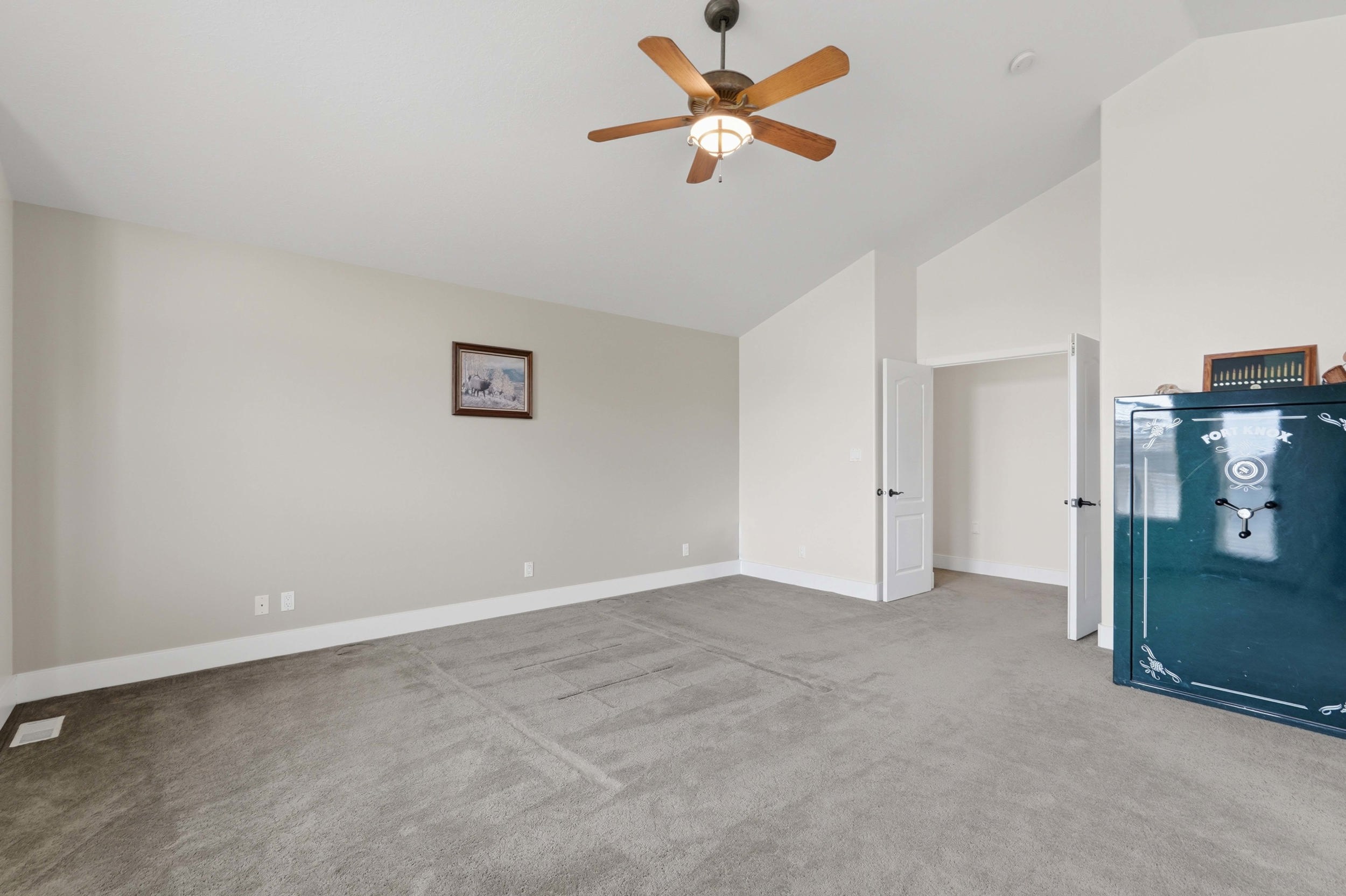 Carpeted room featuring vaulted ceilings, a ceiling fan with light fixture, and white trim