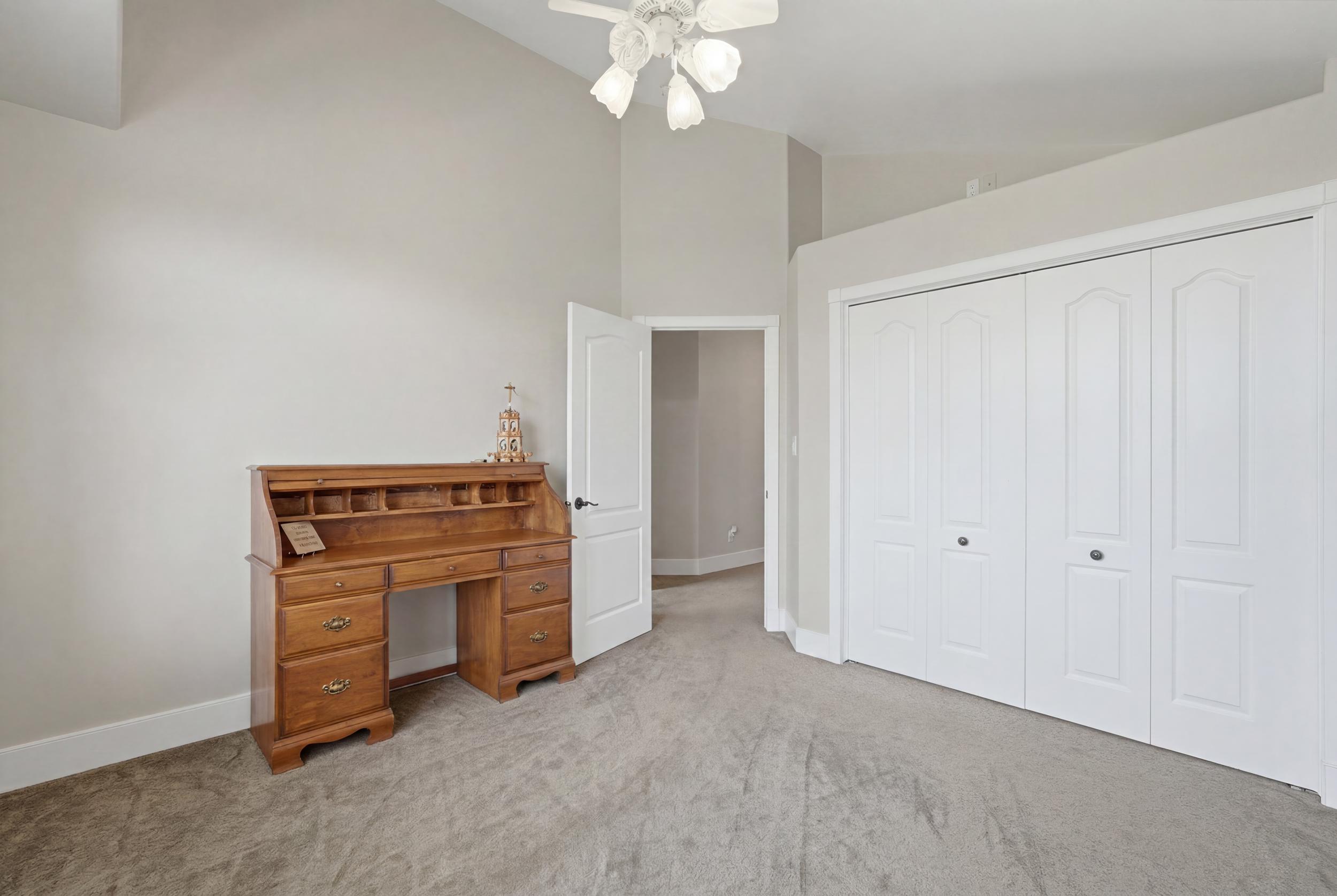 Room featuring vaulted ceilings, plush carpet flooring, and a ceiling fan light fixture