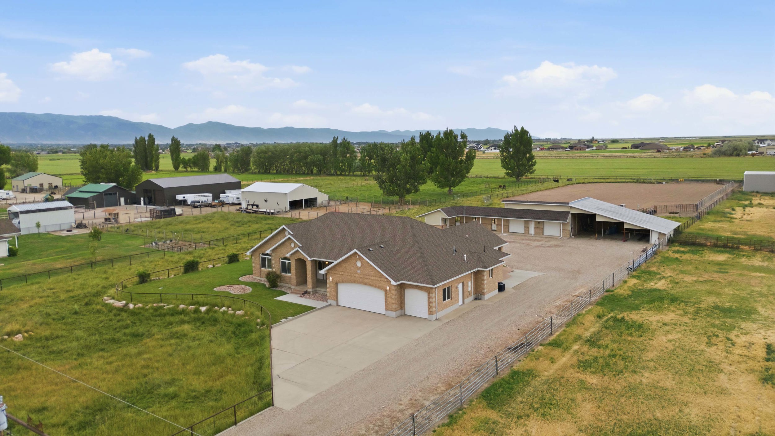Expansive property featuring a single-story residence with a two-car garage, multiple outbuildings, and an equestrian arena
