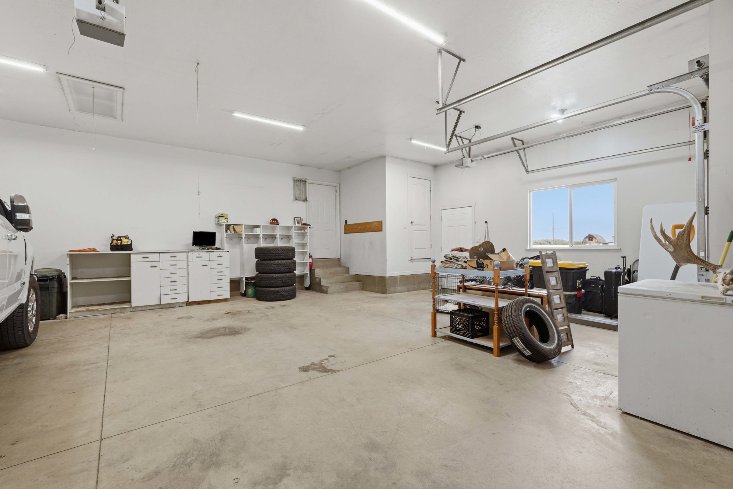 Spacious garage featuring a concrete floor, multiple fluorescent light fixtures, and white walls