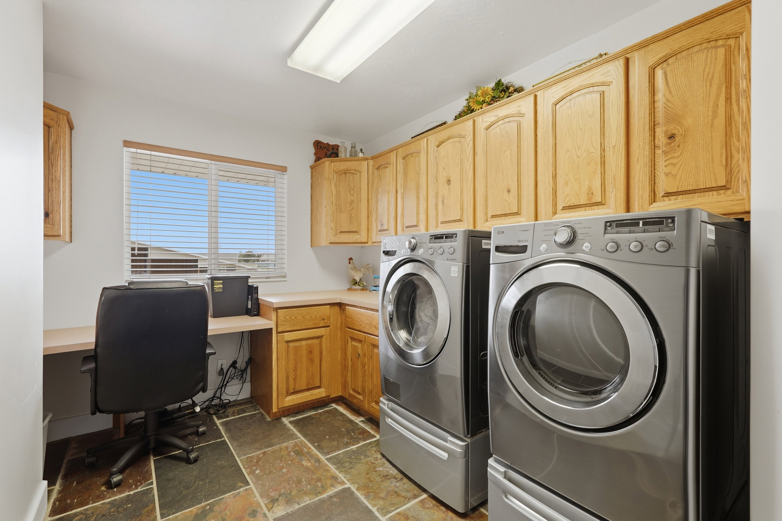 Laundry area with stone tile flooring and ample wood cabinetry