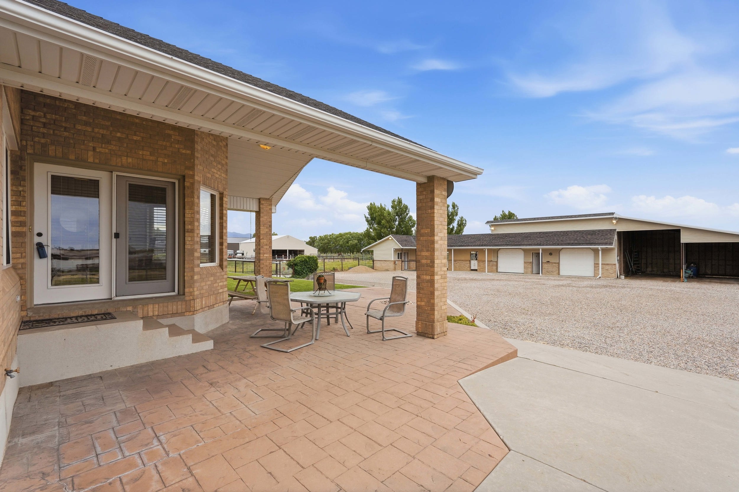 Covered patio featuring stamped concrete flooring, brick columns, and a double glass door entry
