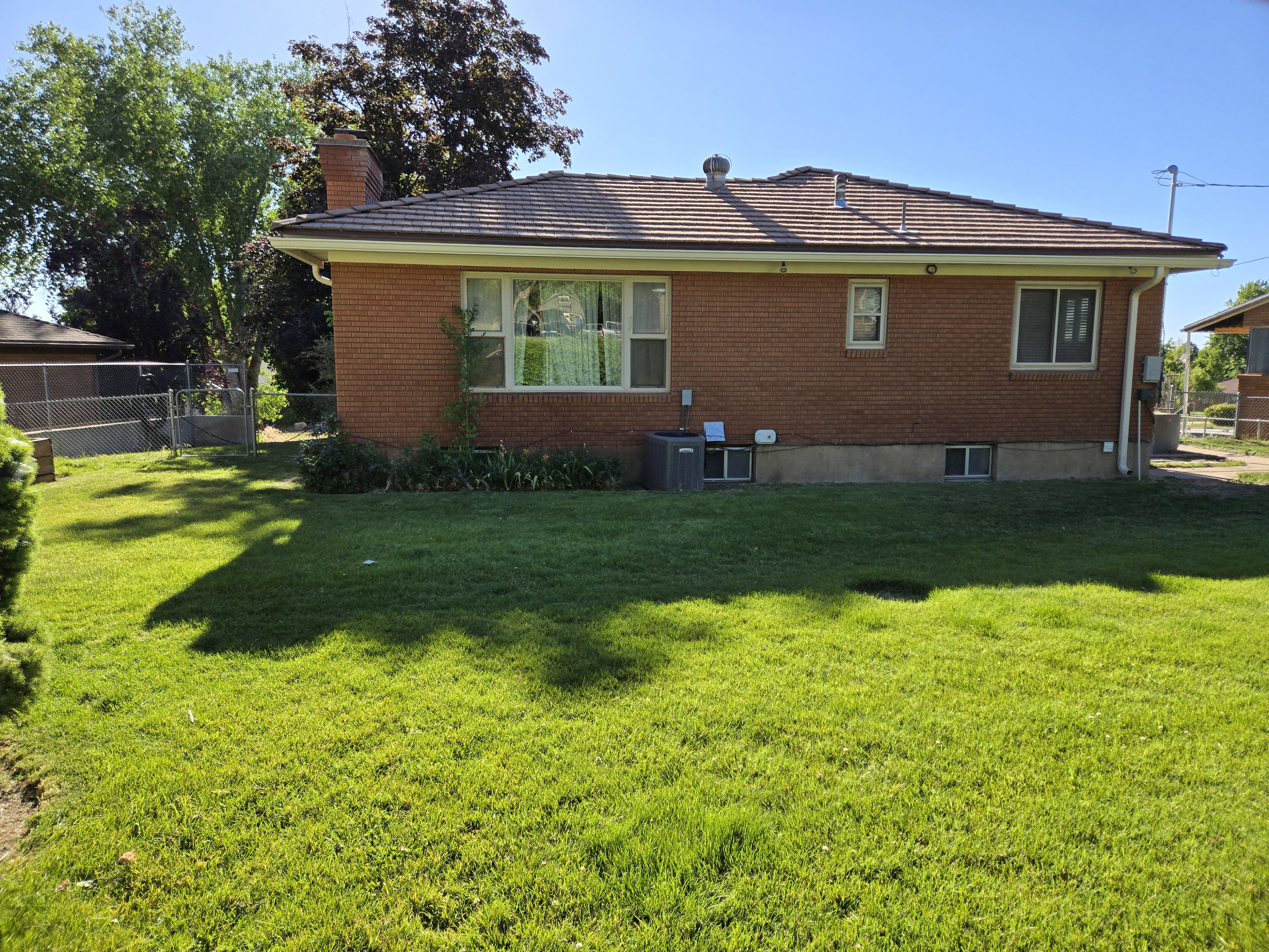 Brick exterior with a tiled roof, featuring multiple windows and a green lawn