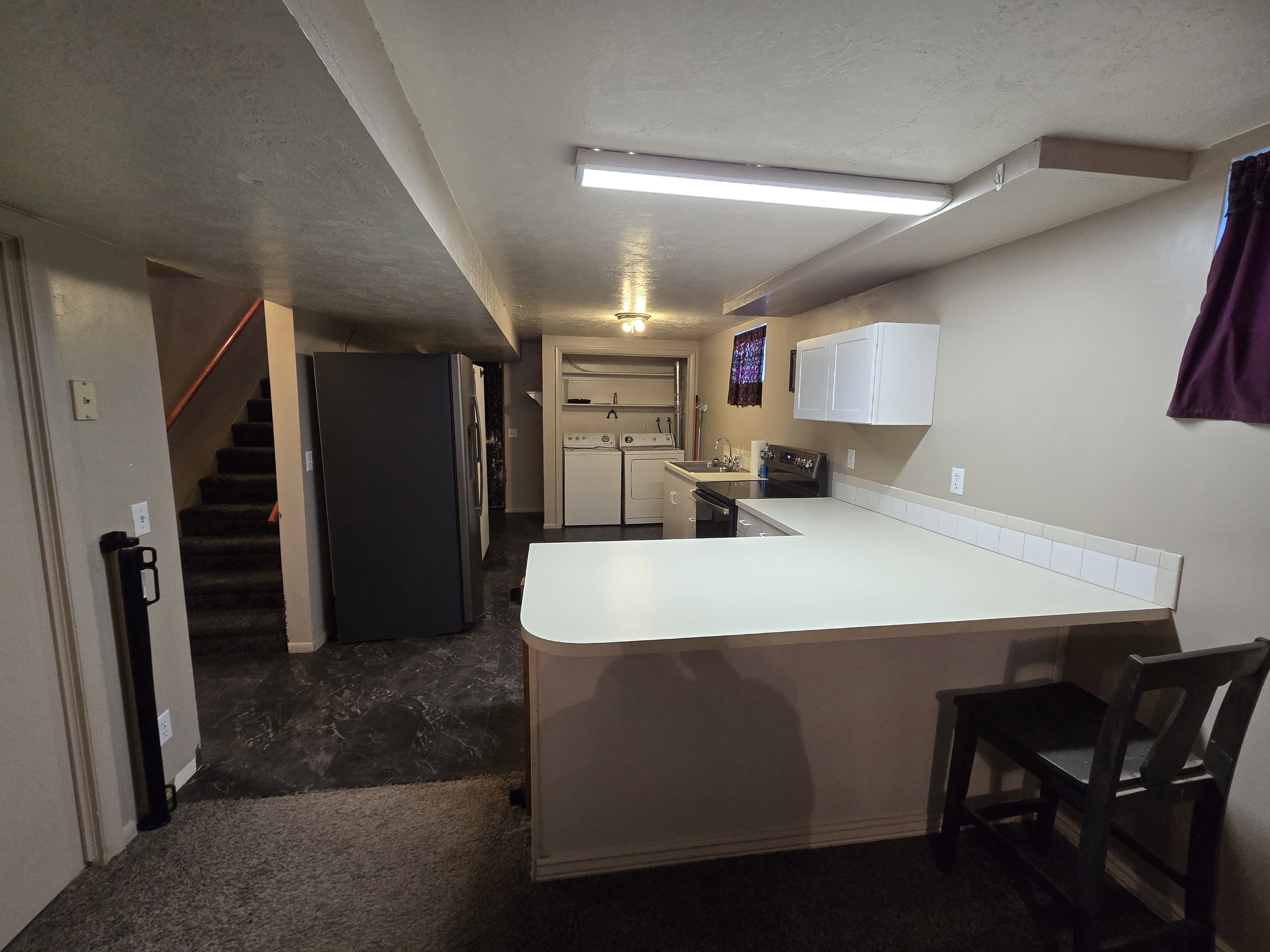Kitchenette featuring white cabinetry, light-colored countertops, and a white tile backsplash