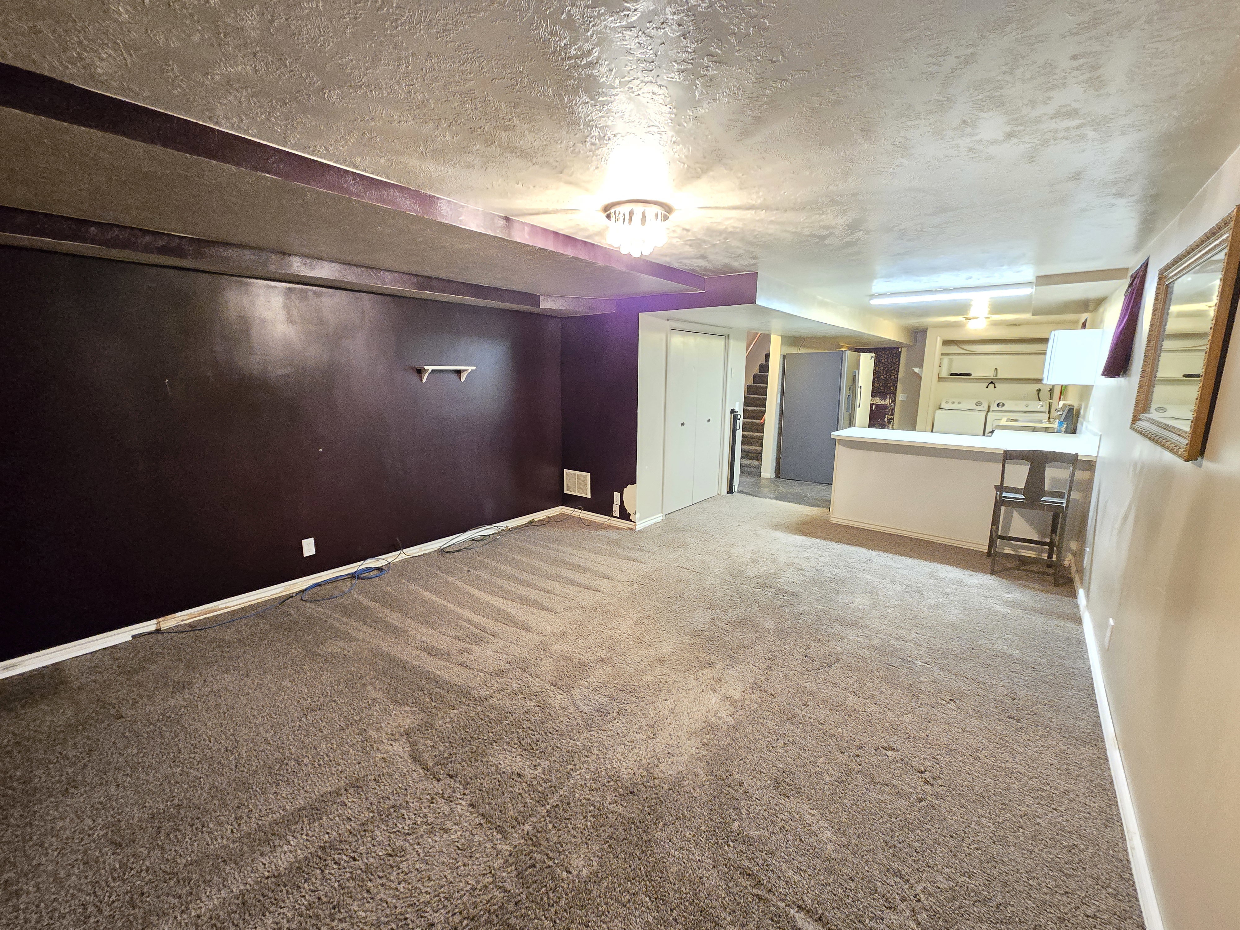 Spacious finished area featuring plush carpeting, a built-in bar, and a utility area