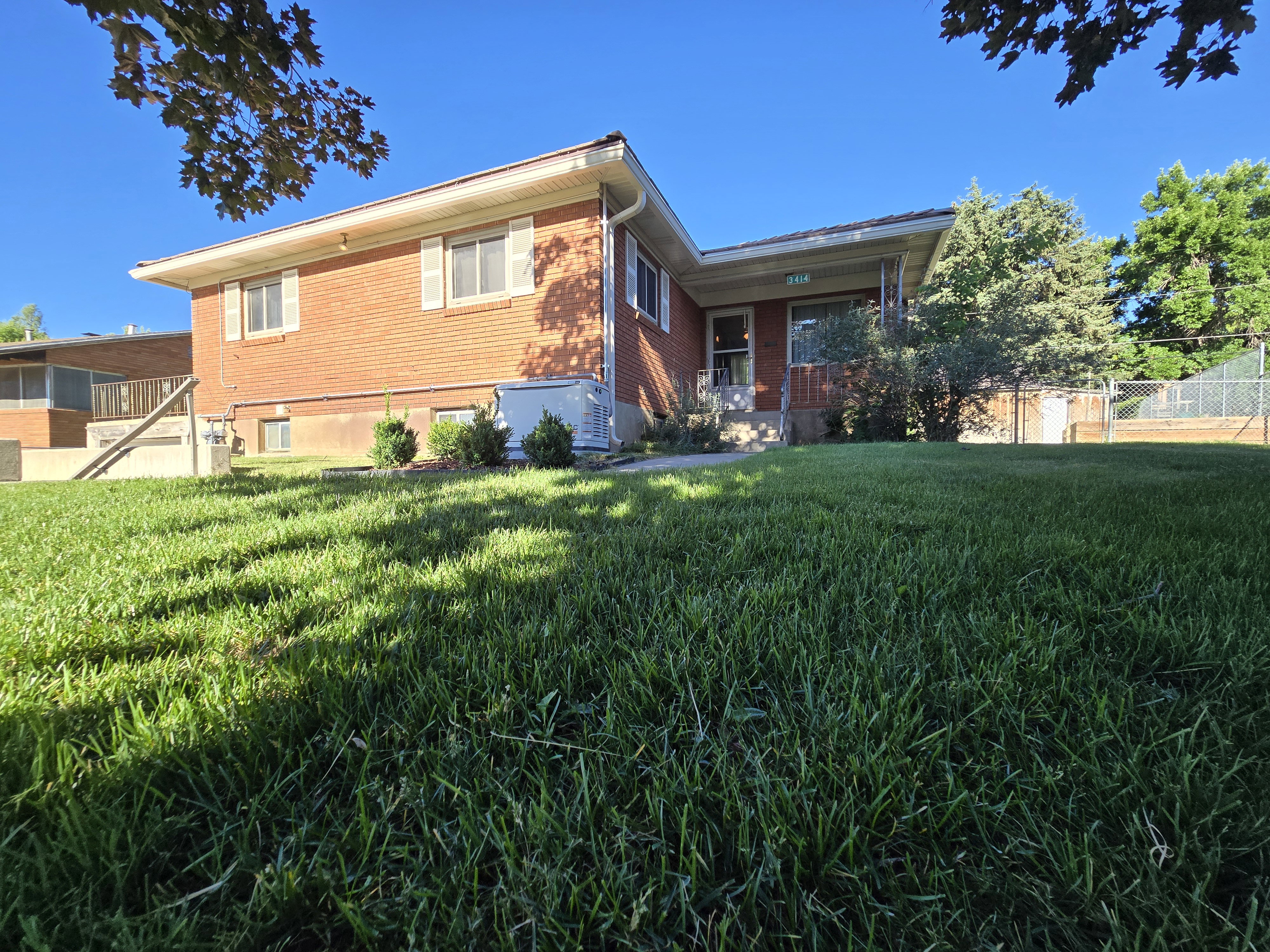 Brick exterior residence featuring white window shutters, a covered front entry, and a sloped lawn