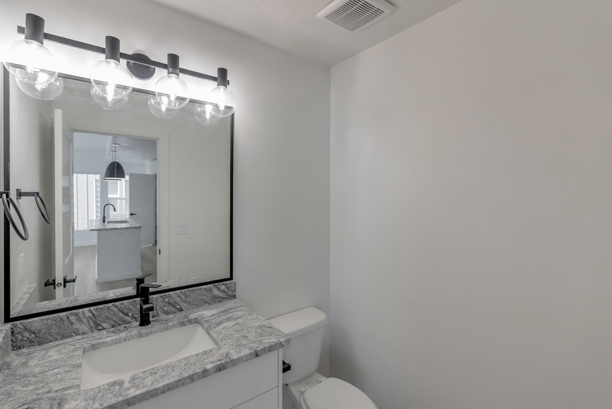 Bathroom vanity with a rectangular undermount sink, stone countertop, and matte black faucet