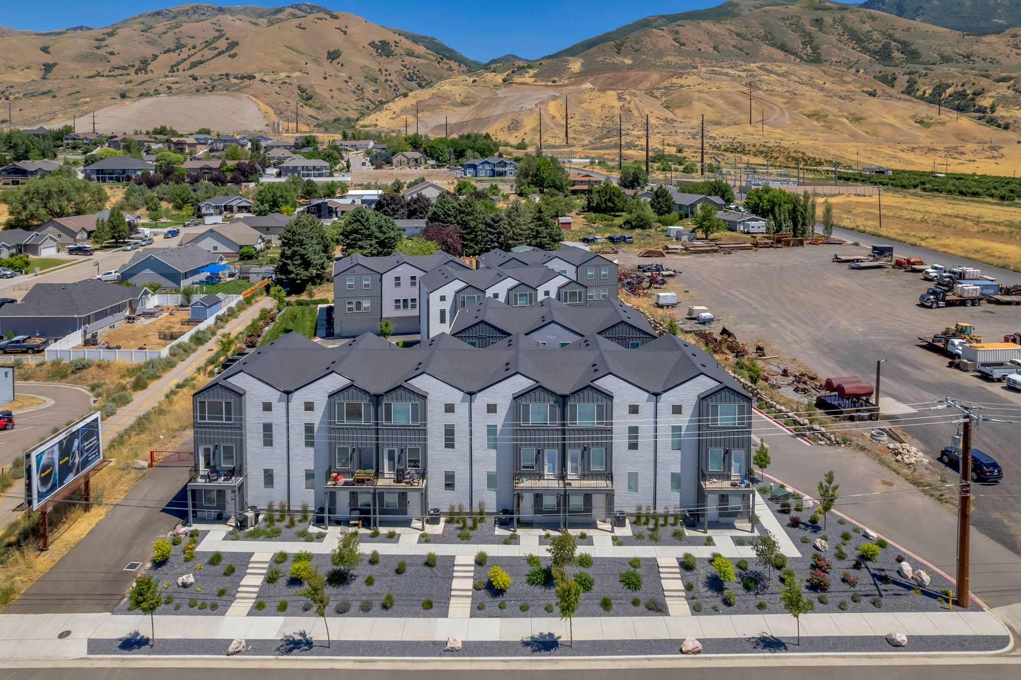 Contemporary multi-story townhome complex featuring a uniform grey and white exterior with dark gabled roofs