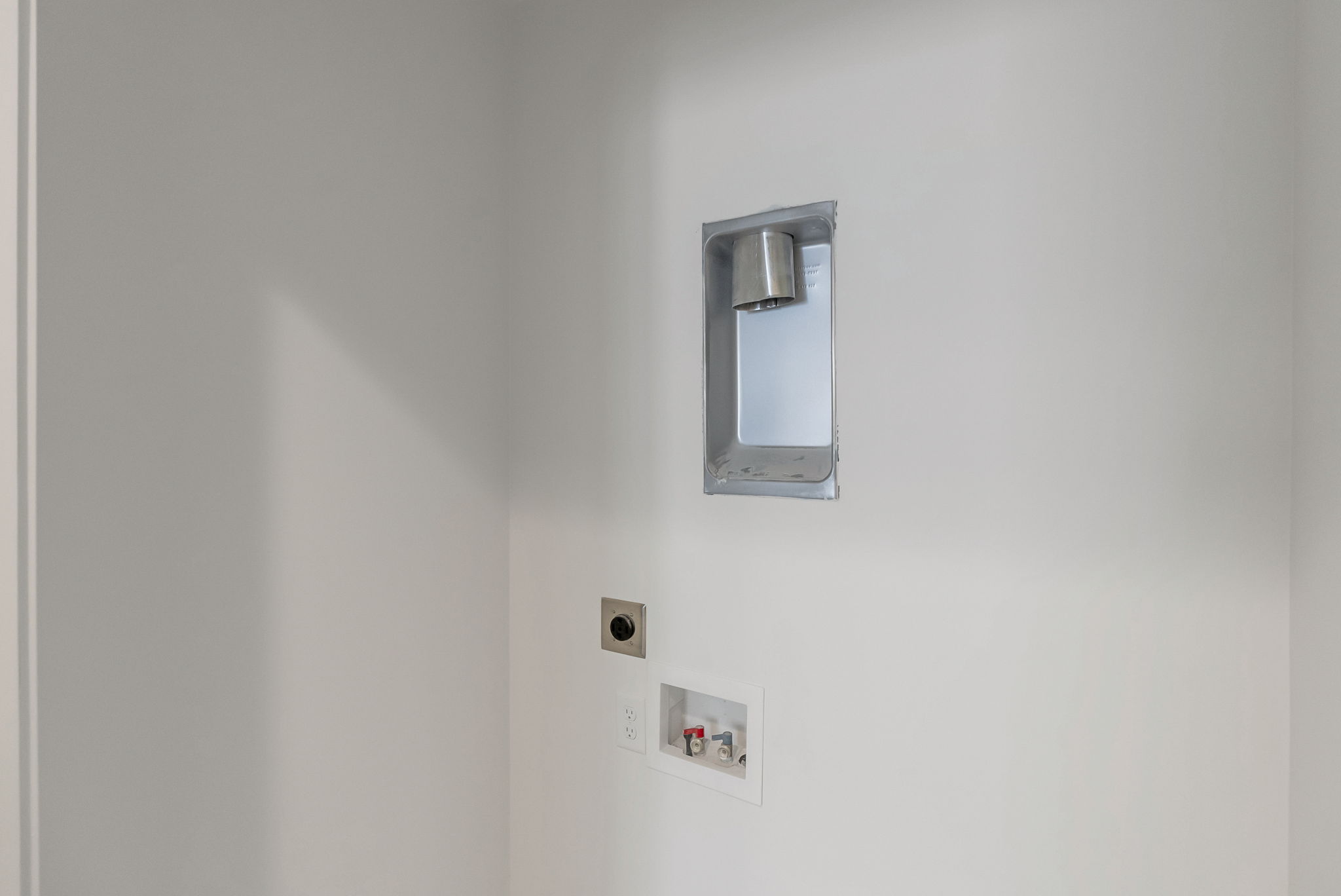 Utility area featuring white walls, a recessed dryer vent, and water hookups