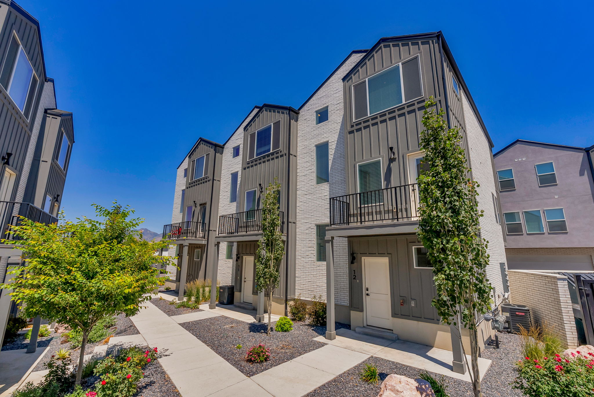 Modern townhome exterior featuring light brick facade and dark vertical siding