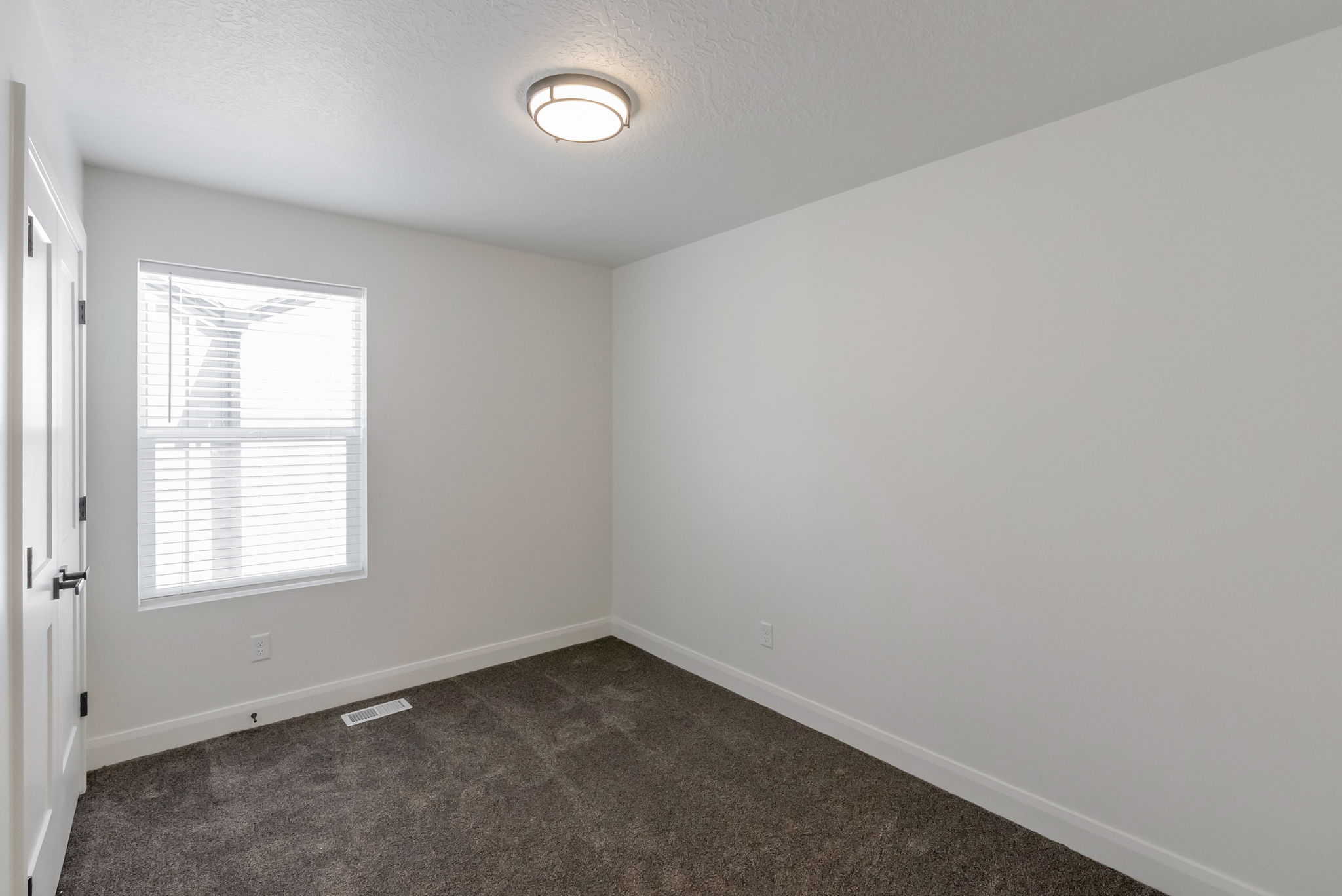 Bright room featuring a window with white blinds, dark gray carpeting, and a flush mount ceiling light fixture