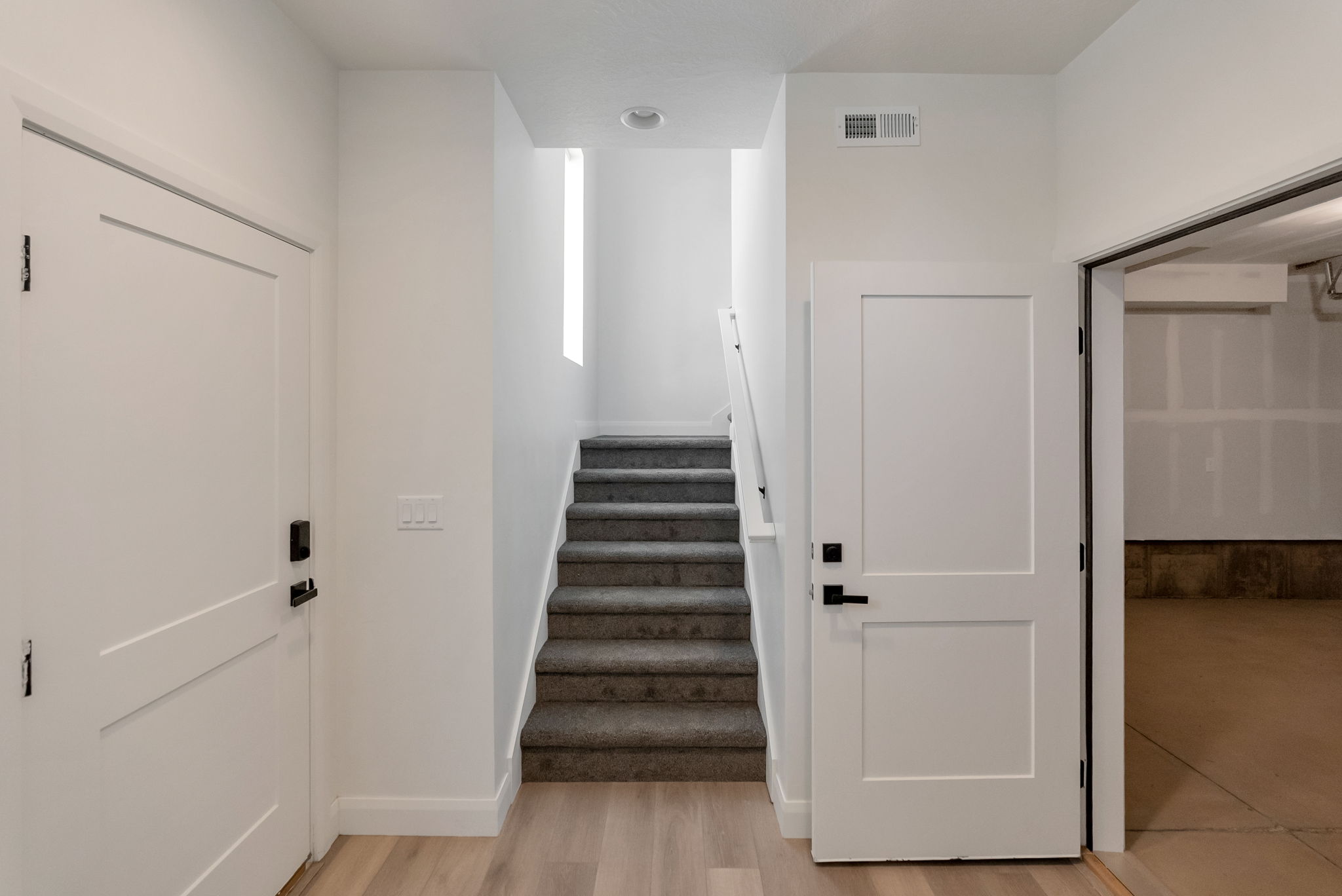 Foyer featuring light wood-finish flooring, white trim, and a staircase with grey carpet