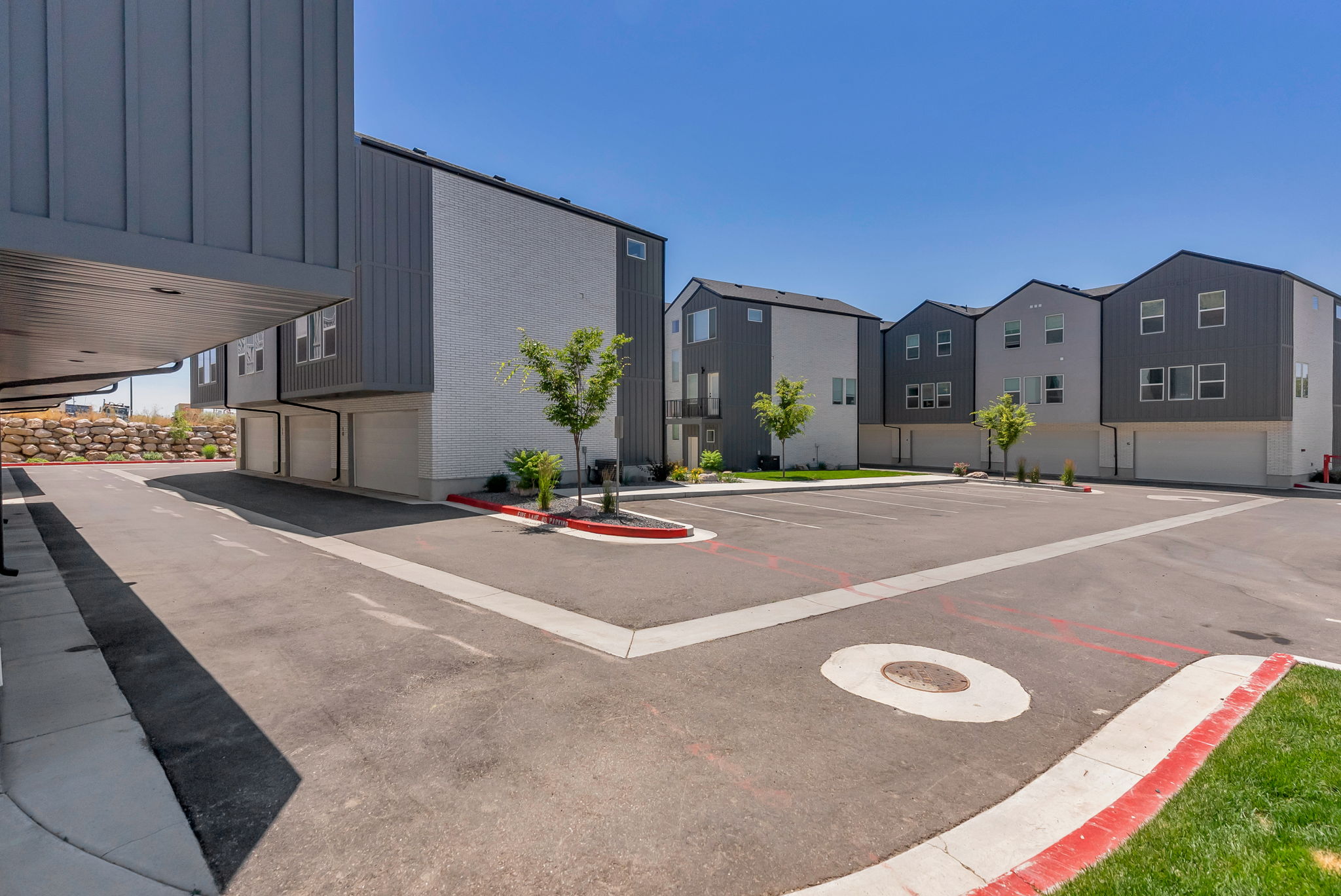 Modern townhome exteriors featuring varied gray siding, white brick accents, and individual garages